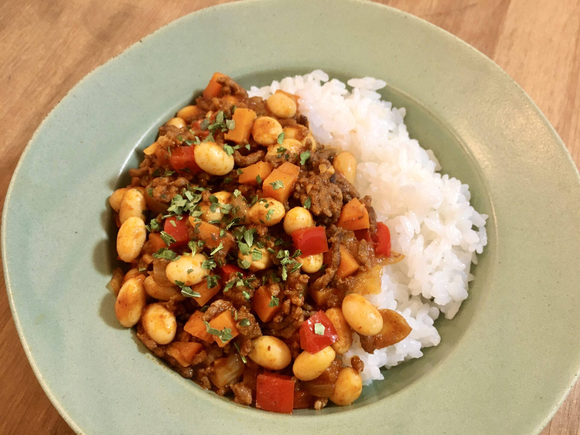 Mexican Food 桌布 壁紙 — 一碗豐盛的豆肉燉菜配米飯，飾以香草，放在木桌上。