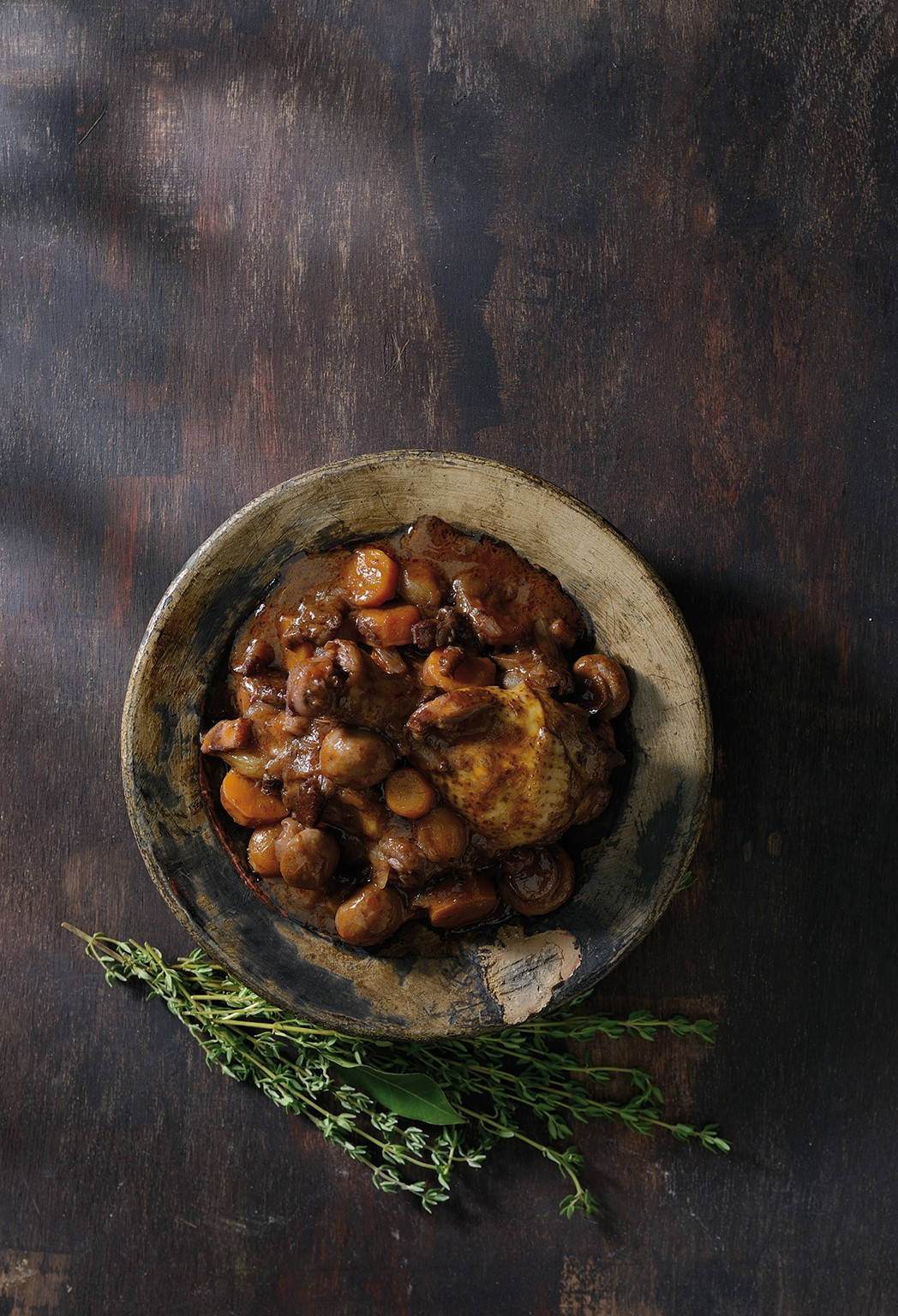 Food Photography 桌布 壁紙 — 一碗鄉村風味濃郁雞肉燉菜，配有紅蘿蔔和蘑菇，放在深色木桌上，旁邊是新鮮百里香。