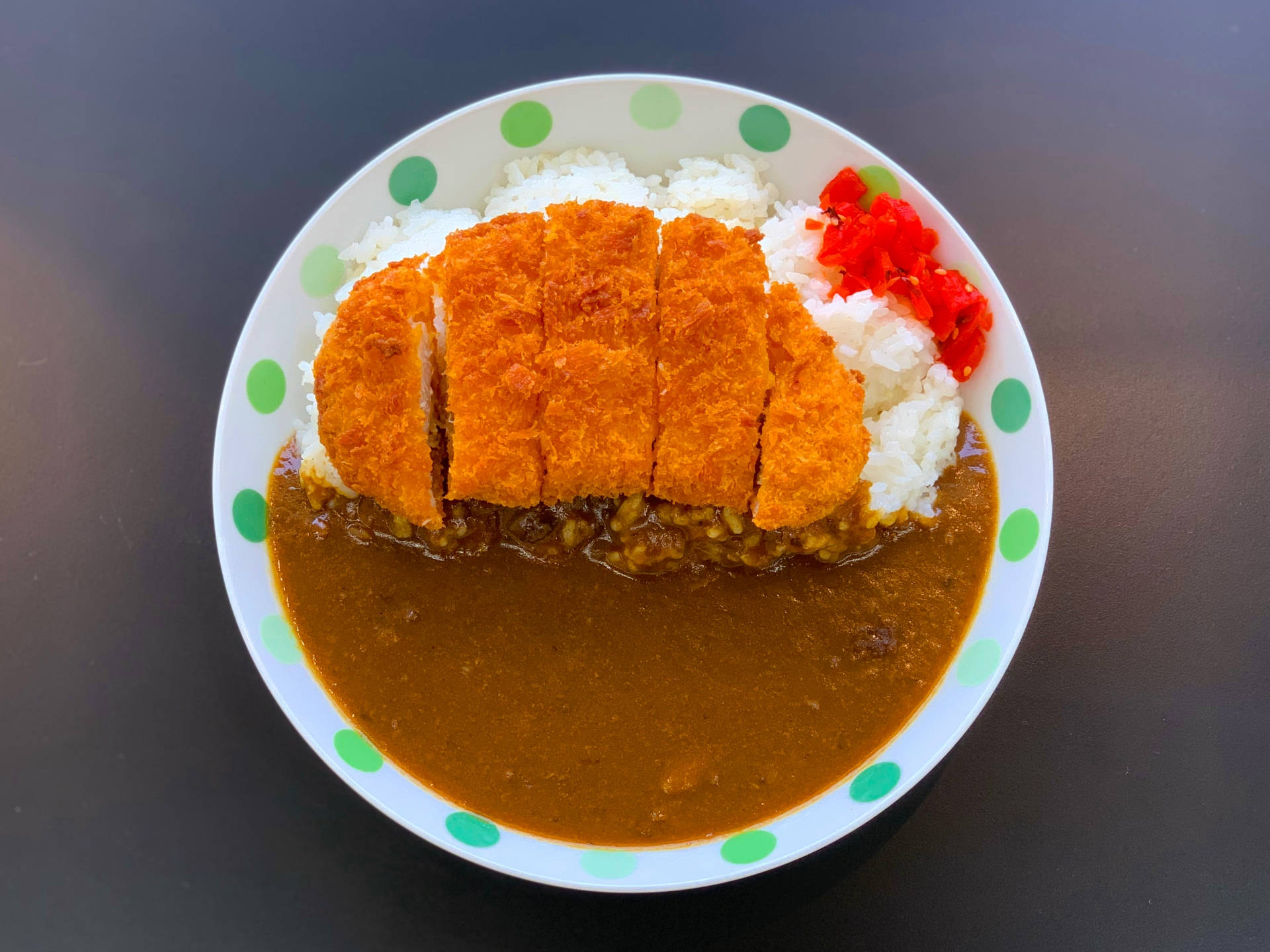 Food Photography 桌布 壁紙 — 一碗金黃酥脆的咖哩豬排飯，配上紅色的醃漬生薑和綠色圓點盤子。