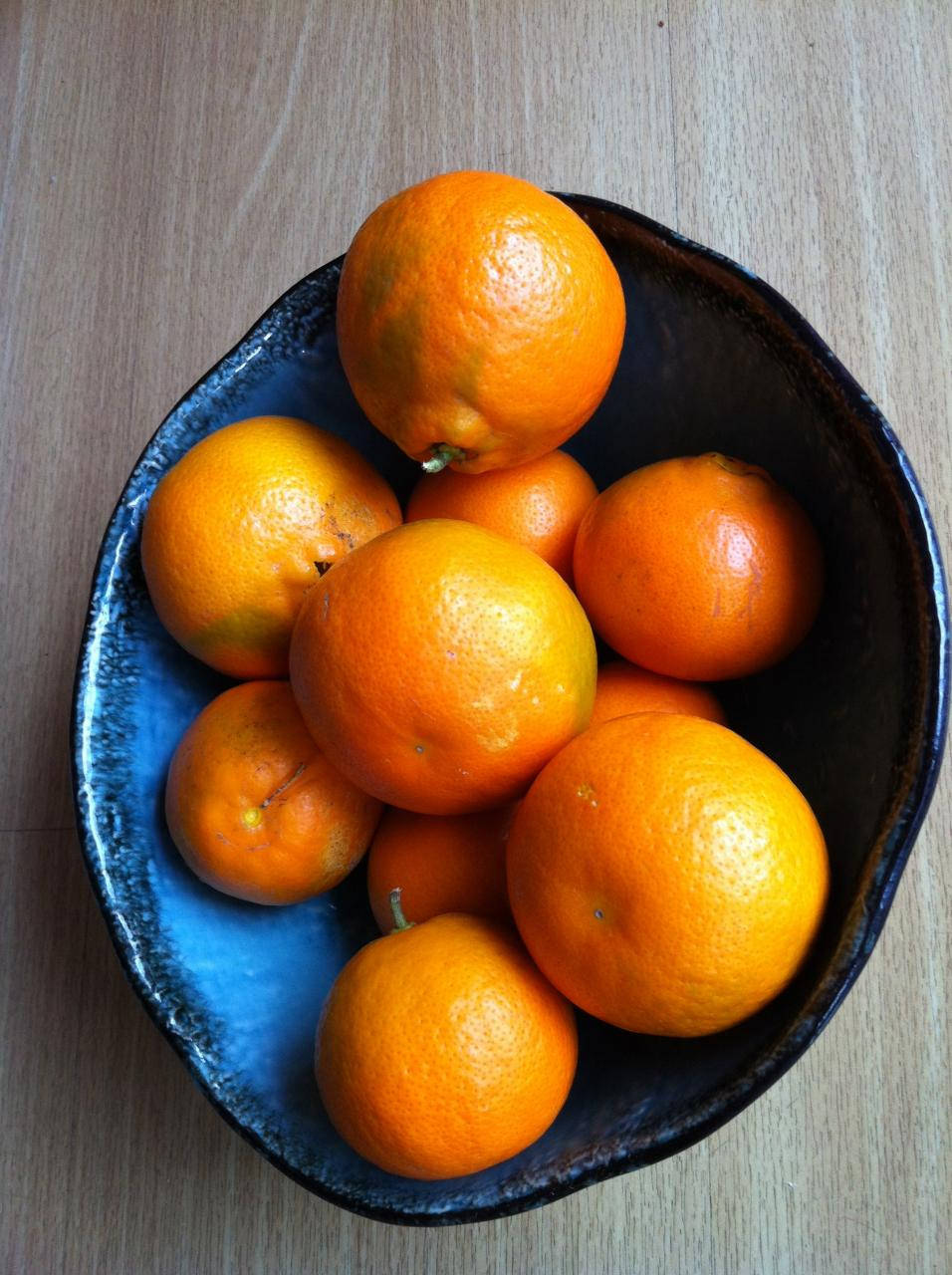 Fruits 桌布 壁紙 — 一碗鮮豔的柳橙放在淺色木質表面上的深藍色陶瓷盤中。