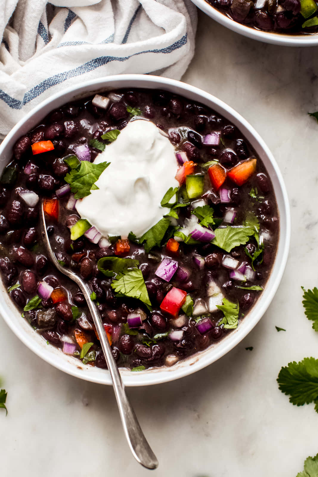 Black Bean Soup 桌布 壁紙 — 一碗黑豆沙拉，上面放有酸奶油、香菜和切丁蔬菜，置於大理石表面上。