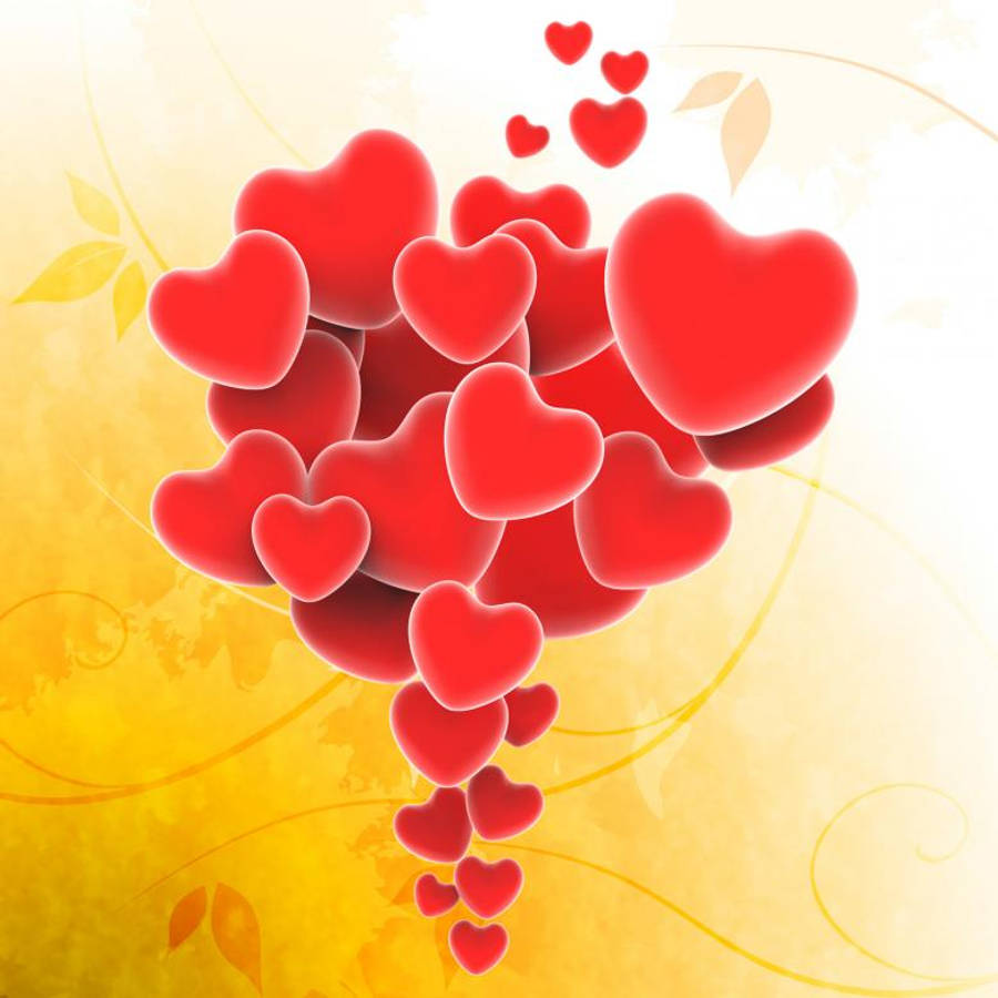 Beautiful Hearts 桌布 壁紙 — 一簇光澤的紅色心形在溫暖的黃色紋理背景上向下傾瀉，帶有微妙的葉子漩渦。