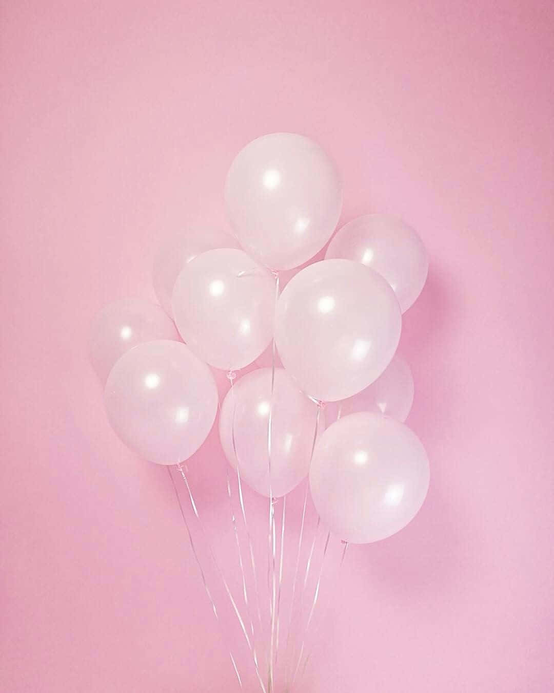 Pastel Pink Aesthetic 桌布 壁紙 — 一簇半透明的粉紅色氣球在柔和的粉紅色背景上輕輕漂浮。