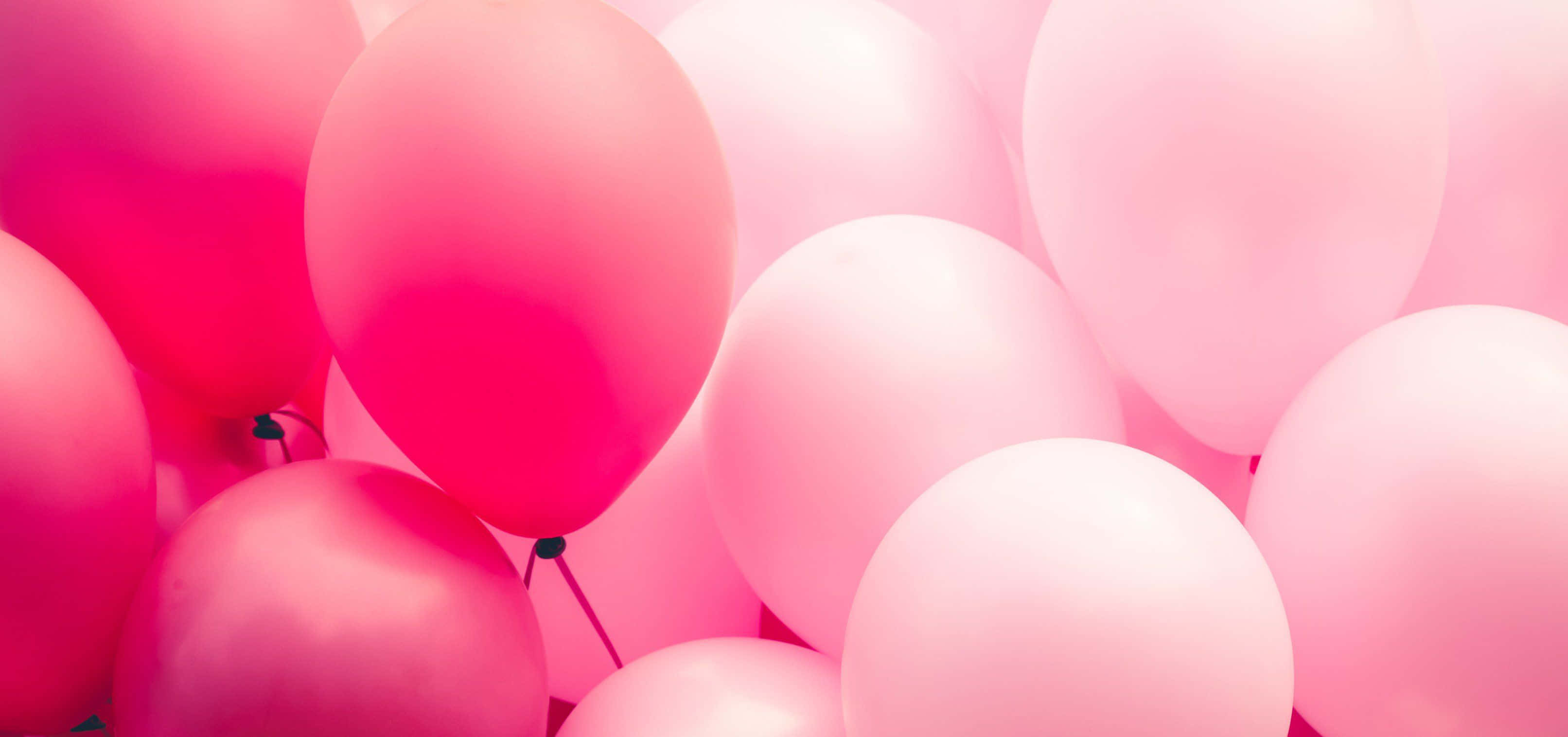 Pink Balloons 桌布 壁紙 — 一簇柔和的粉紅色和紫紅色氣球，在模糊背景前發出柔和光線。