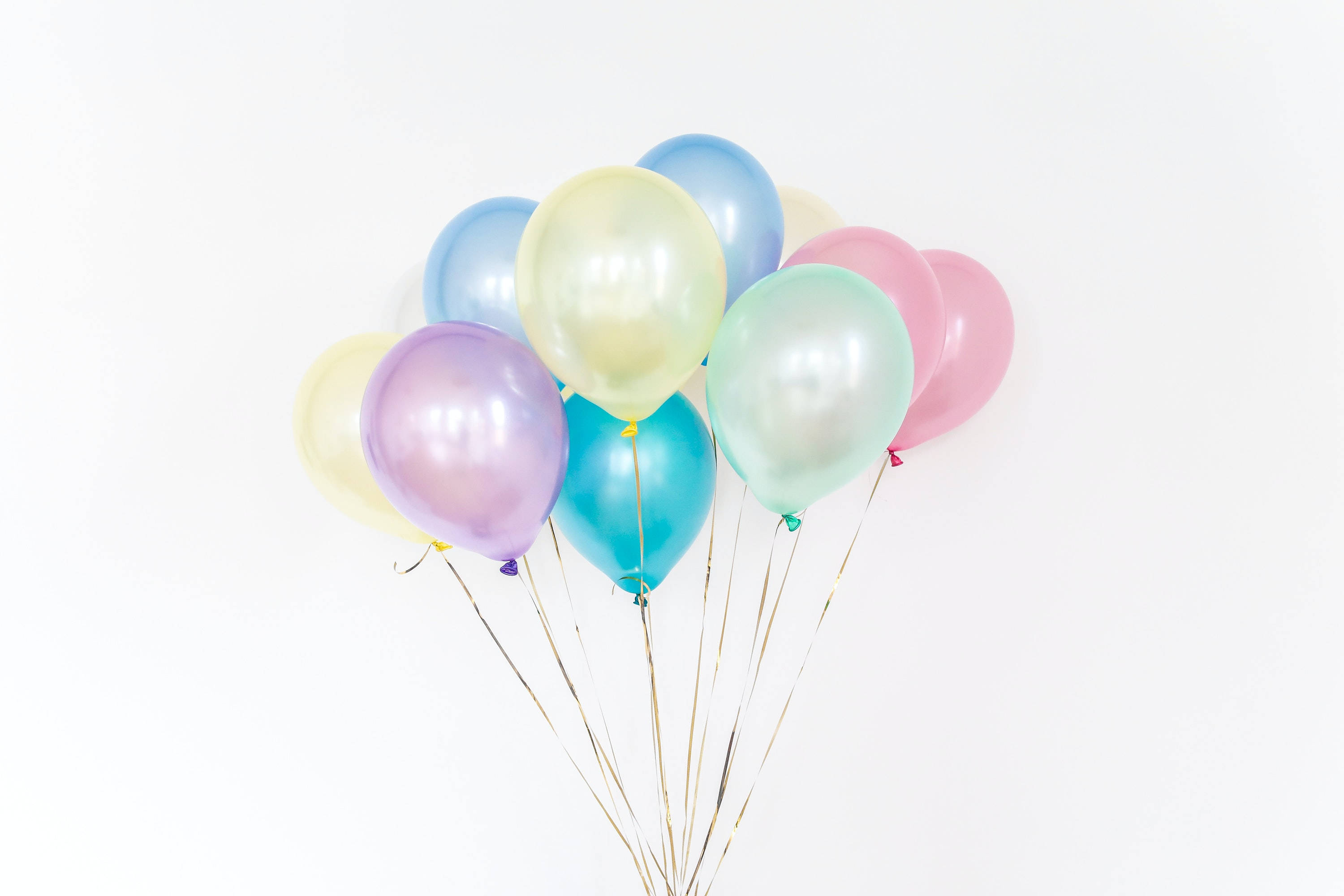 Balloons 桌布 壁紙 — 一簇粉彩金屬氣球，繫著金色繩子，漂浮在潔白背景上。