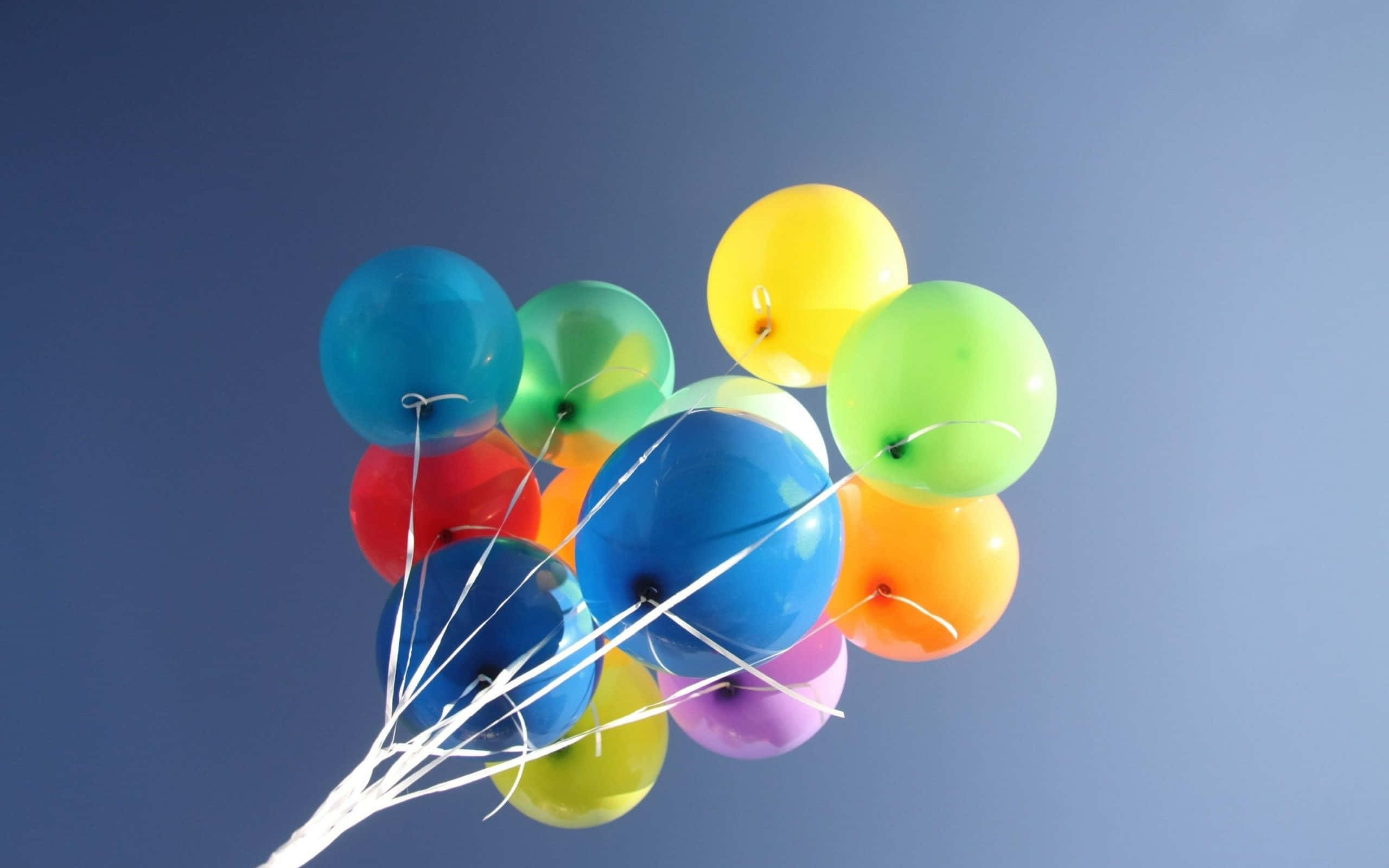 Balloon 桌布 壁紙 — 一簇色彩繽紛的氣球在晴朗的藍天中飄浮，由白色繩子繫著。