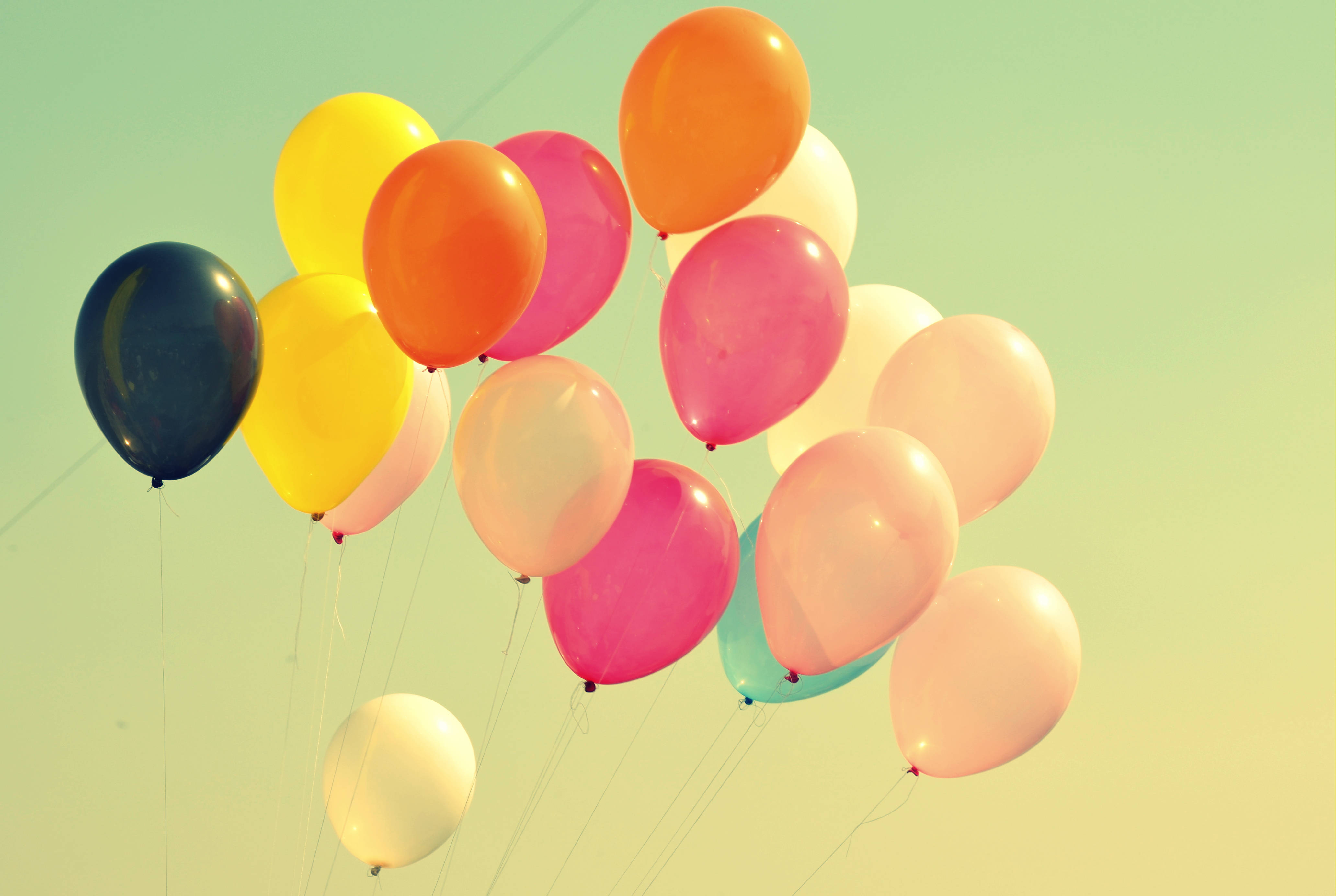 Balloon 桌布 壁紙 — 一簇色彩繽紛的氣球在柔和漸變的天空中飄浮，帶有溫暖的復古色調。