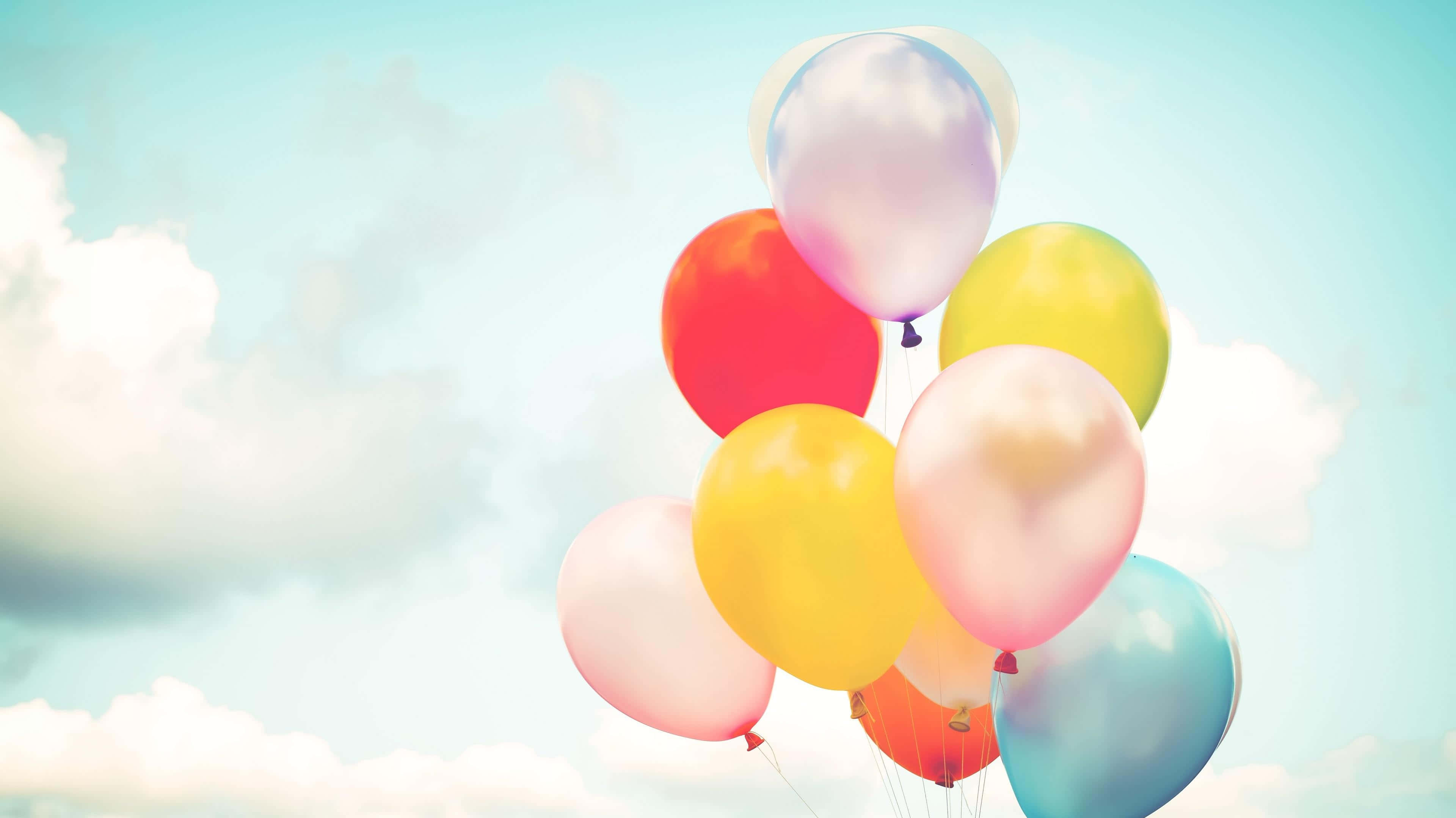 Balloon 桌布 壁紙 — 一簇色彩繽紛的氣球在柔和的藍天和白雲中輕輕飄浮。