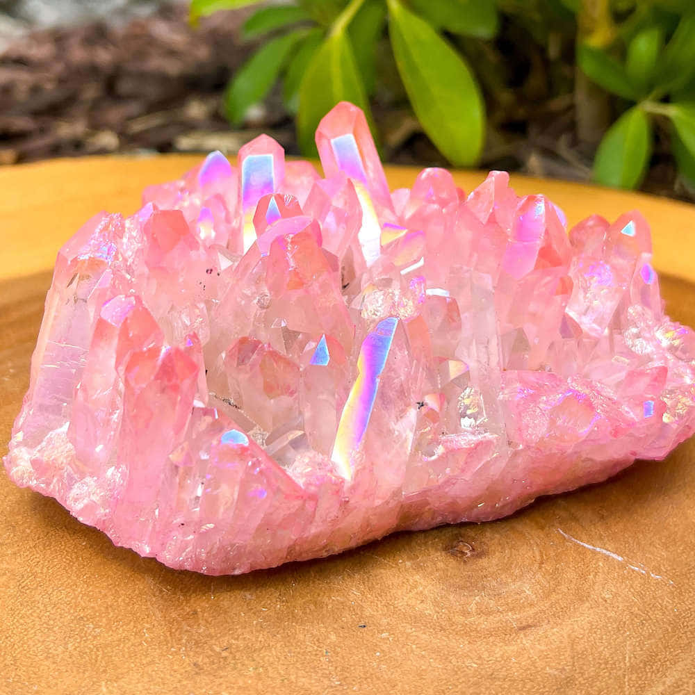 Pink Crystal Quartz 桌布 壁紙 — 一簇虹彩粉紅色水晶在溫暖的木質表面上閃爍著彩虹色調。
