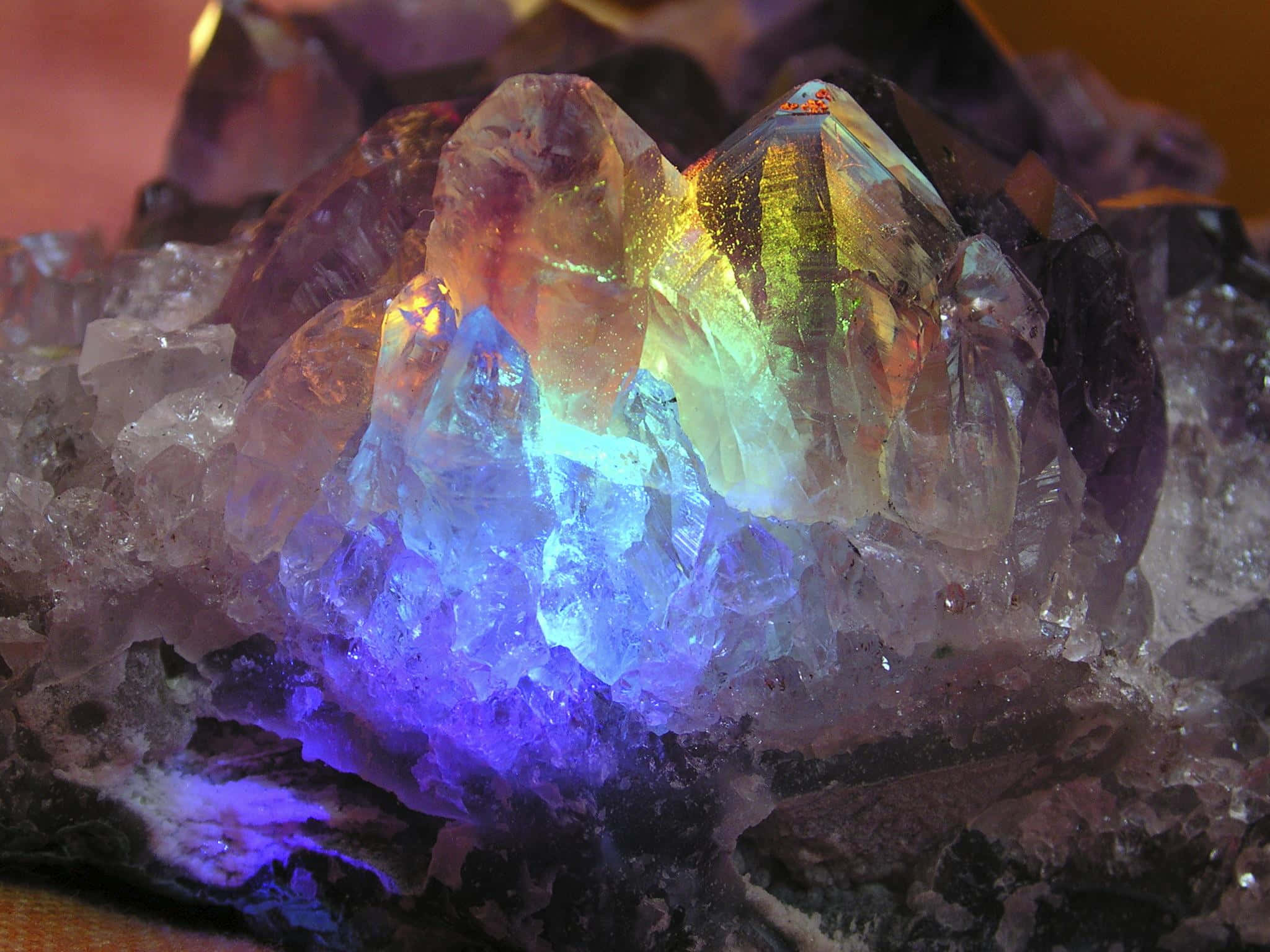 水晶 桌布 壁紙 — 一簇閃耀的紫水晶，在戲劇性的燈光下散發出鮮豔的藍色、紫色和金色色調。
