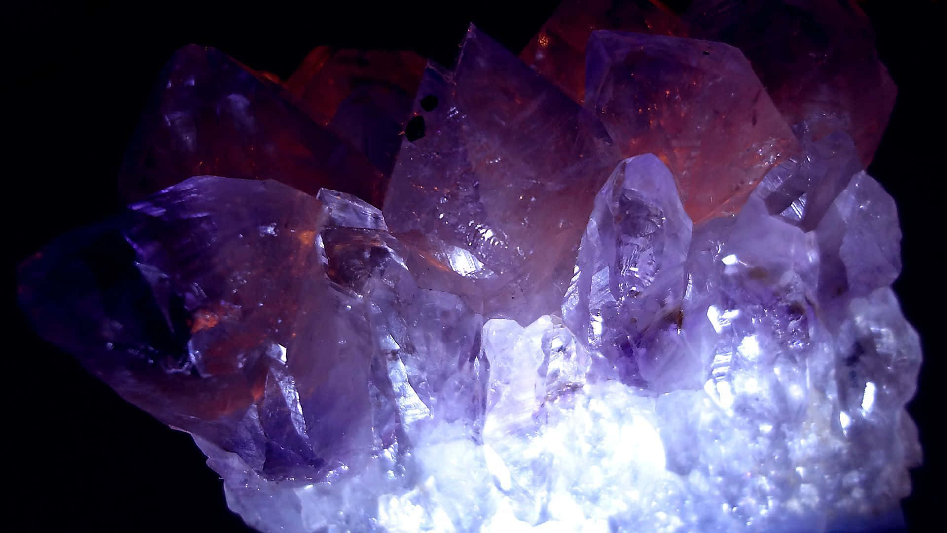 紫水晶 桌布 壁紙 — 一簇閃耀的紫水晶在純黑背景下散發著充滿活力的紫色和白色光芒。