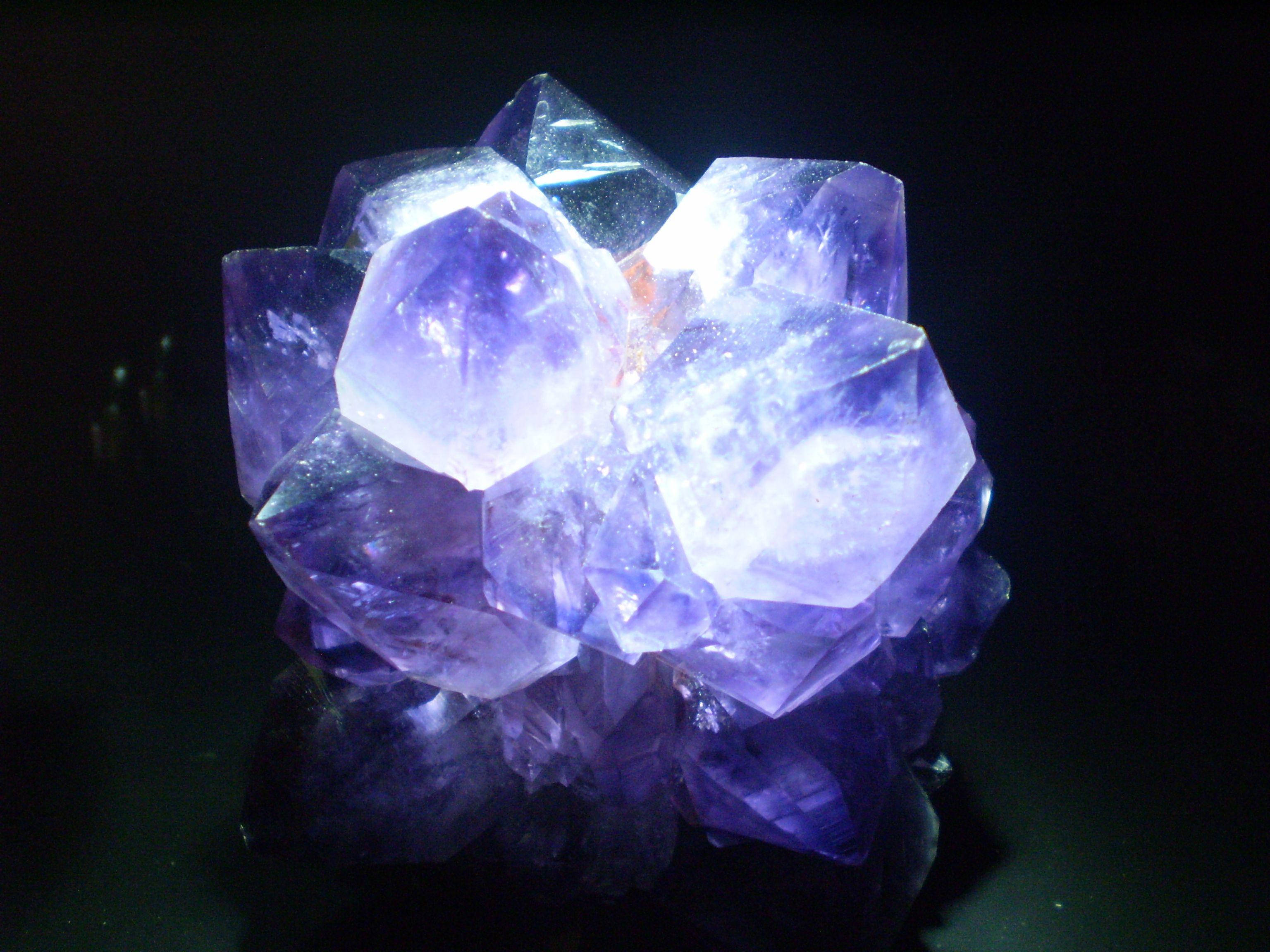 紫水晶 桌布 壁紙 — 一簇閃耀的紫水晶晶體在純黑背景下散發出深紫色光芒。