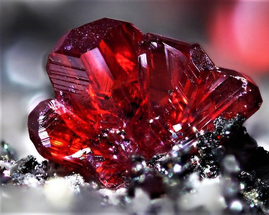 Red Crystal 桌布 壁紙 — 一簇鮮豔的紅色水晶在模糊的金屬背景上閃耀著銳利的切面和內部反射。