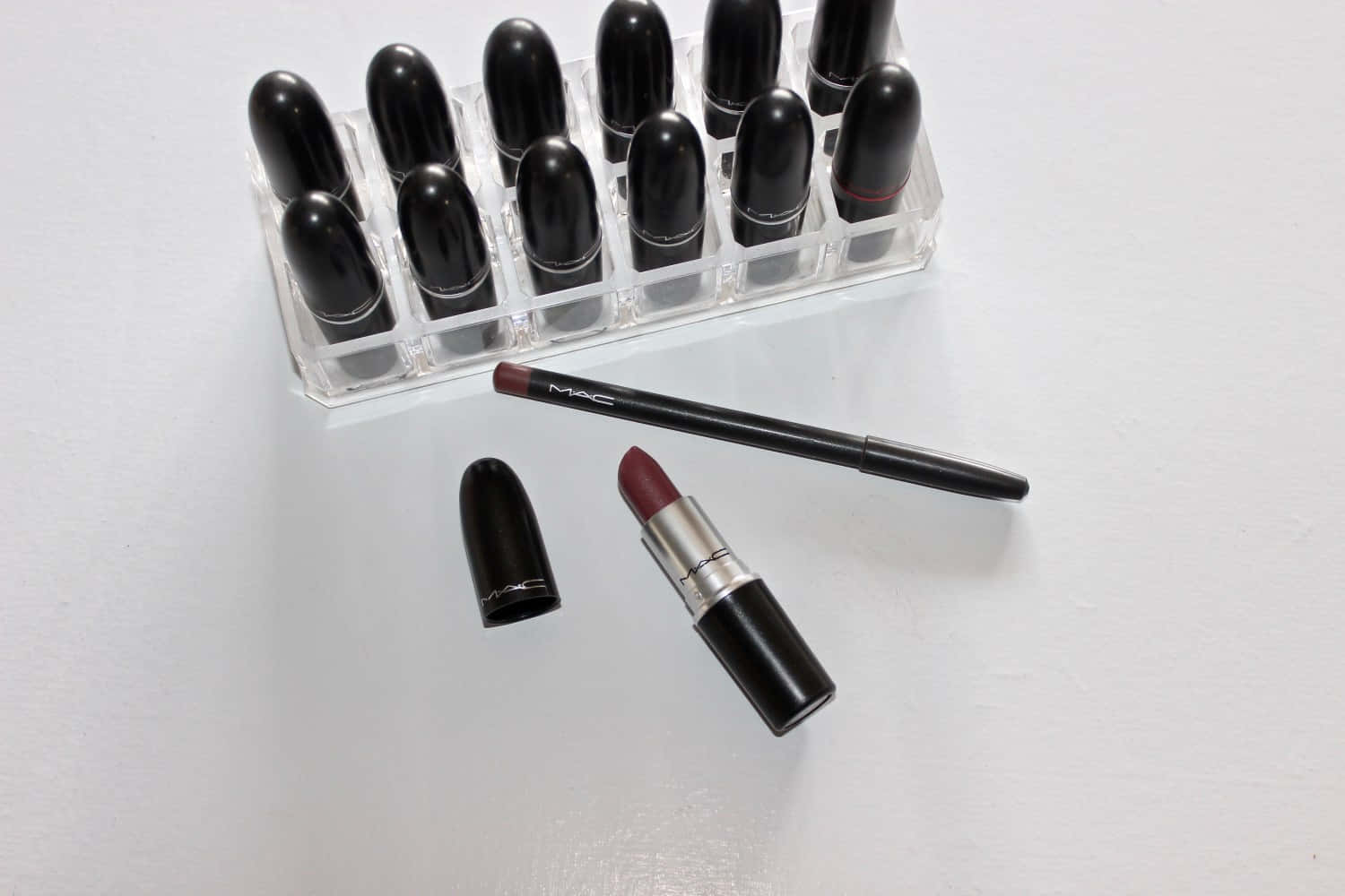 Mac Cosmetics 桌布 壁紙 — 一系列MAC唇膏和唇線筆整齊地排列在乾淨的白色表面上。