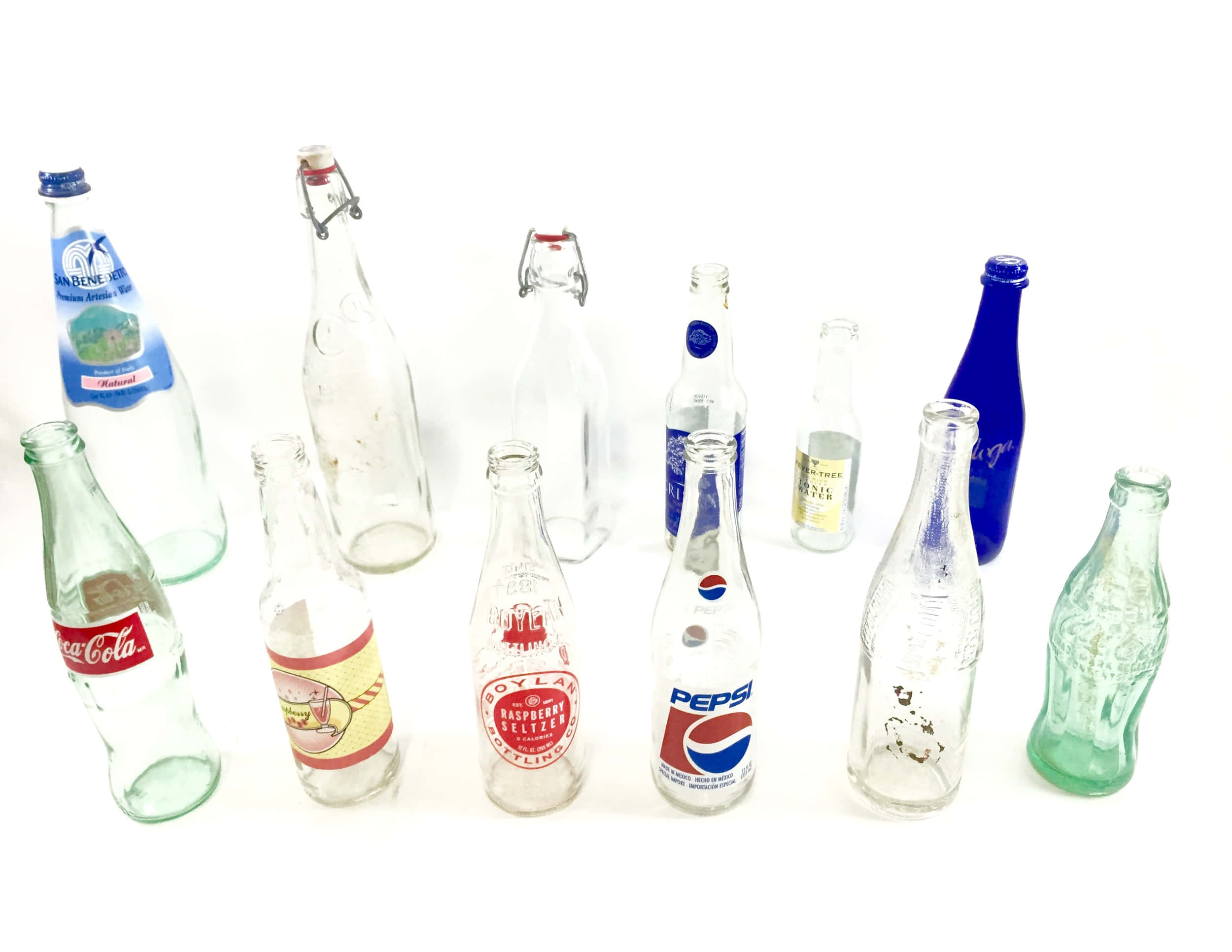 Old Bottles 桌布 壁紙 — 一系列不同形狀和顏色的復古玻璃汽水瓶，排列在白色背景上。