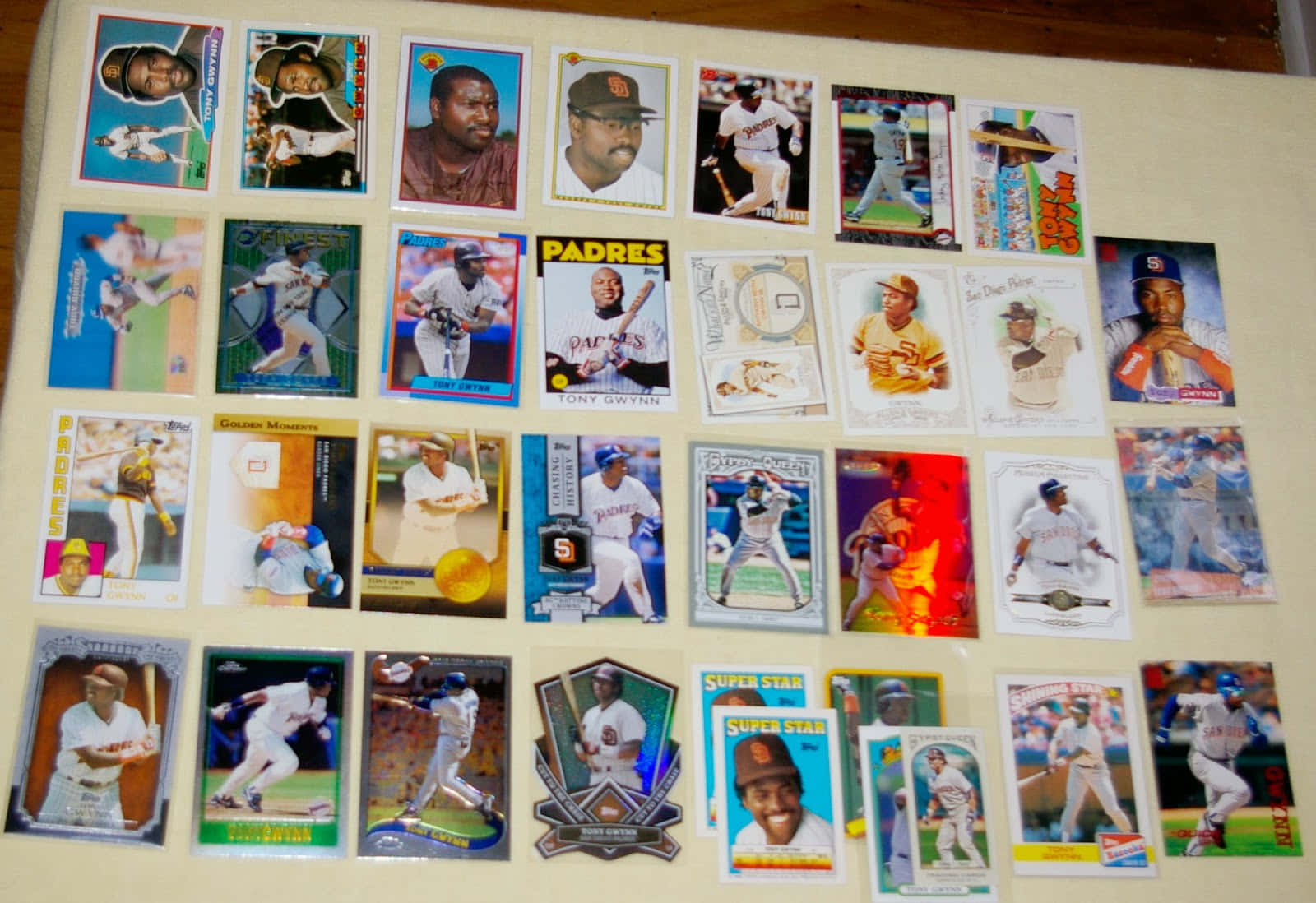 Baseball Cards 桌布 壁紙 — 一系列充滿活力的復古棒球交換卡整齊地排列在米色表面上，展示了不同球隊制服和時代的球員動作和肖像。