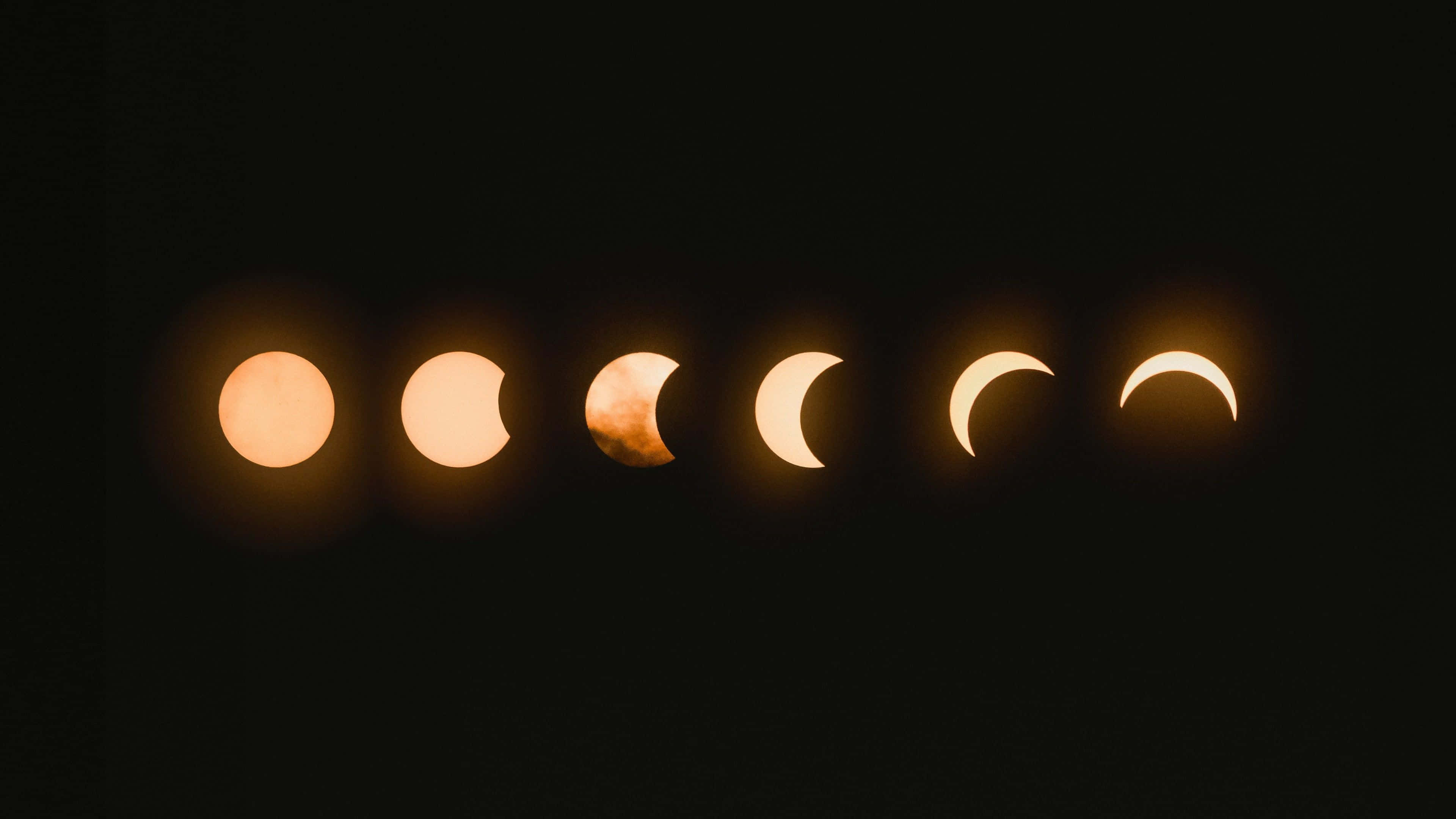 Moon Phases 桌布 壁紙 — 一系列六個日食階段，在黑色天空中發出琥珀色光芒，顯示月球逐漸覆蓋太陽。