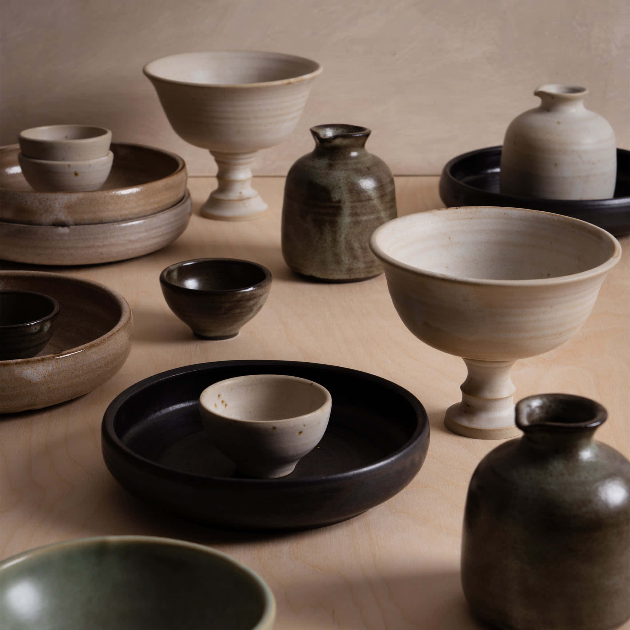 Ceramic 桌布 壁紙 — 一系列手工製作的陶瓷碗、花瓶和盤子，以大地色調排列在木質表面上。