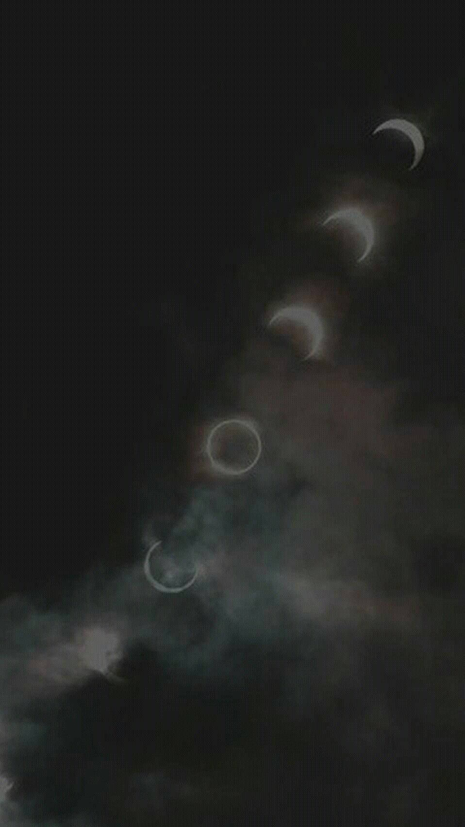 Moon Phases 桌布 壁紙 — 一系列月食階段，在黑色天空中透過暗雲隱約發光。