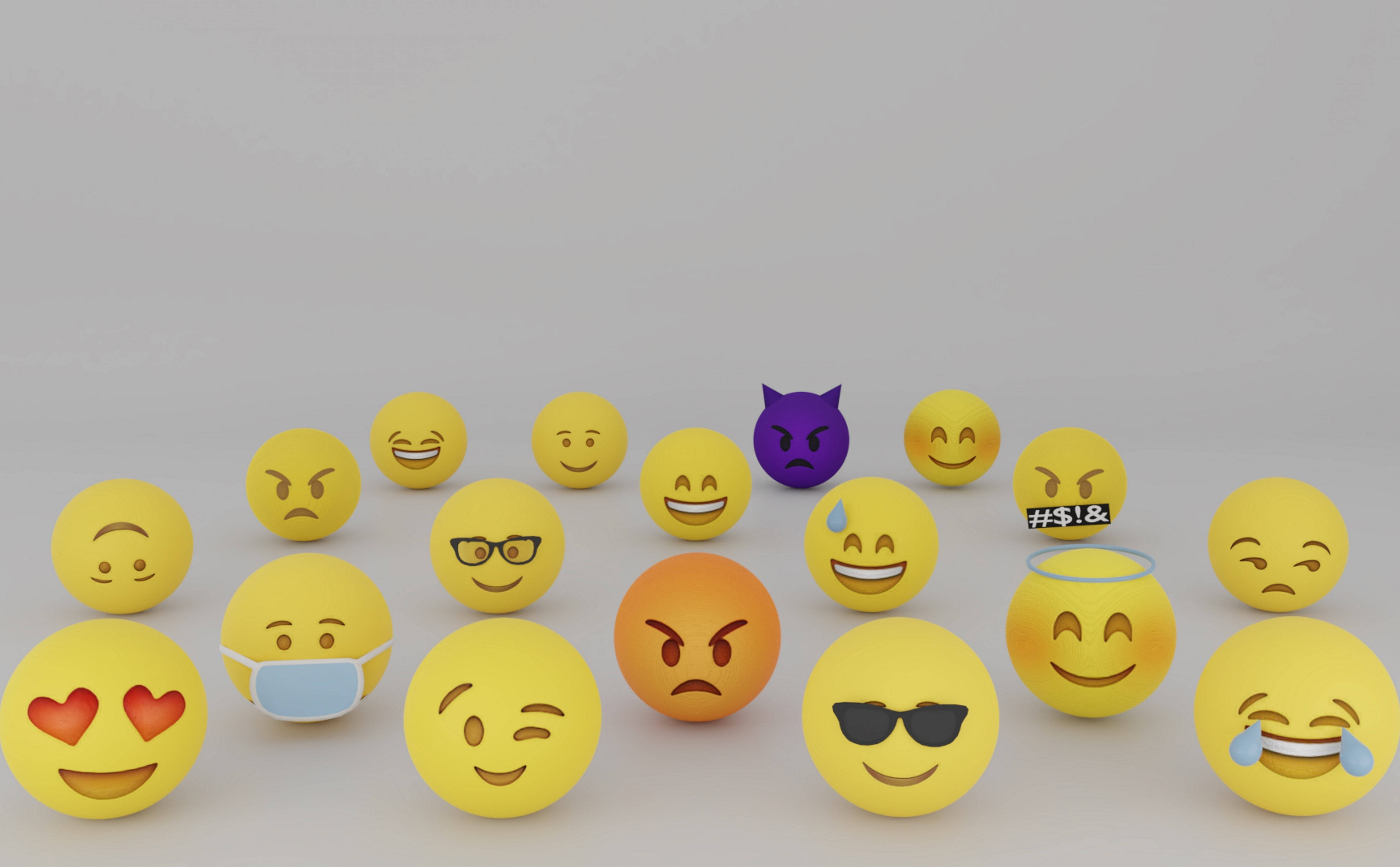 Emotions 桌布 壁紙 — 一系列色彩繽紛的3D表情符號球體，在純灰色背景上展示從笑到怒的各種表情。