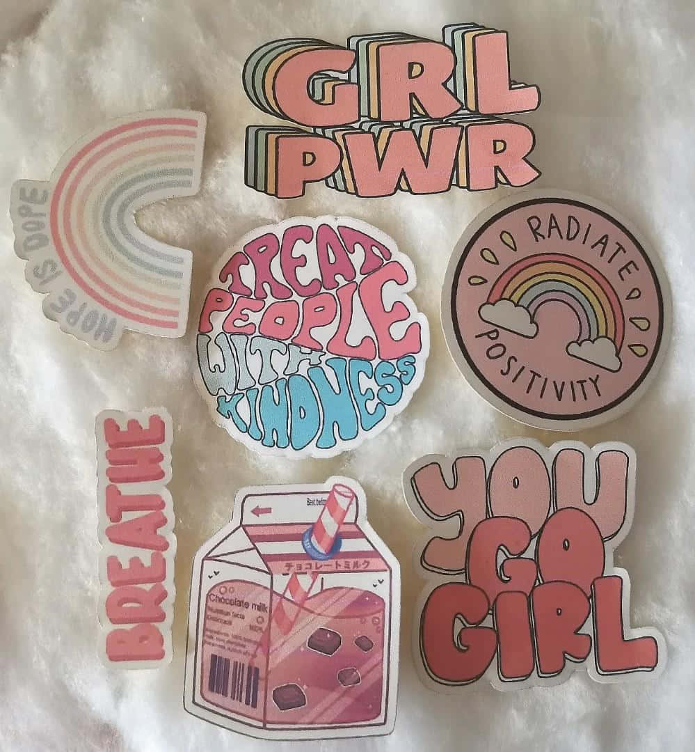 Aesthetic Retro 桌布 壁紙 — 一系列色彩繽紛的勵志貼紙，上面有「GRL PWR」和「TREAT PEOPLE WITH KINDNESS」等短語，排列在毛茸茸的白色表面上。