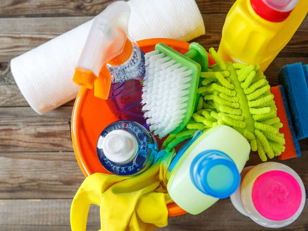 Cleaning 桌布 壁紙 — 一系列色彩繽紛的清潔用品，包括刷子、海綿和瓶子，整齊地擺放在木質表面上。