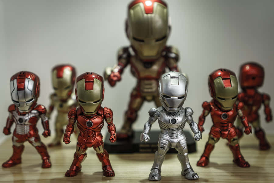 Iron Man Action Figures 桌布 壁紙 — 一系列身穿紅色、金色和銀色裝甲的鋼鐵人動作人偶在木質表面上擺出姿勢。