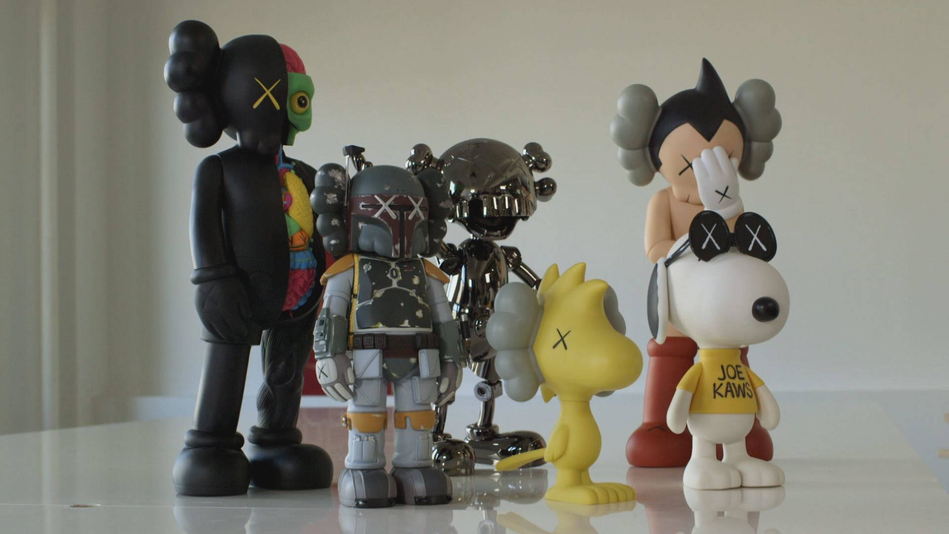 KAWS 桌布 壁紙 — 一系列風格化的KAWS人偶和流行文化玩具，排列在反光的白色表面上。