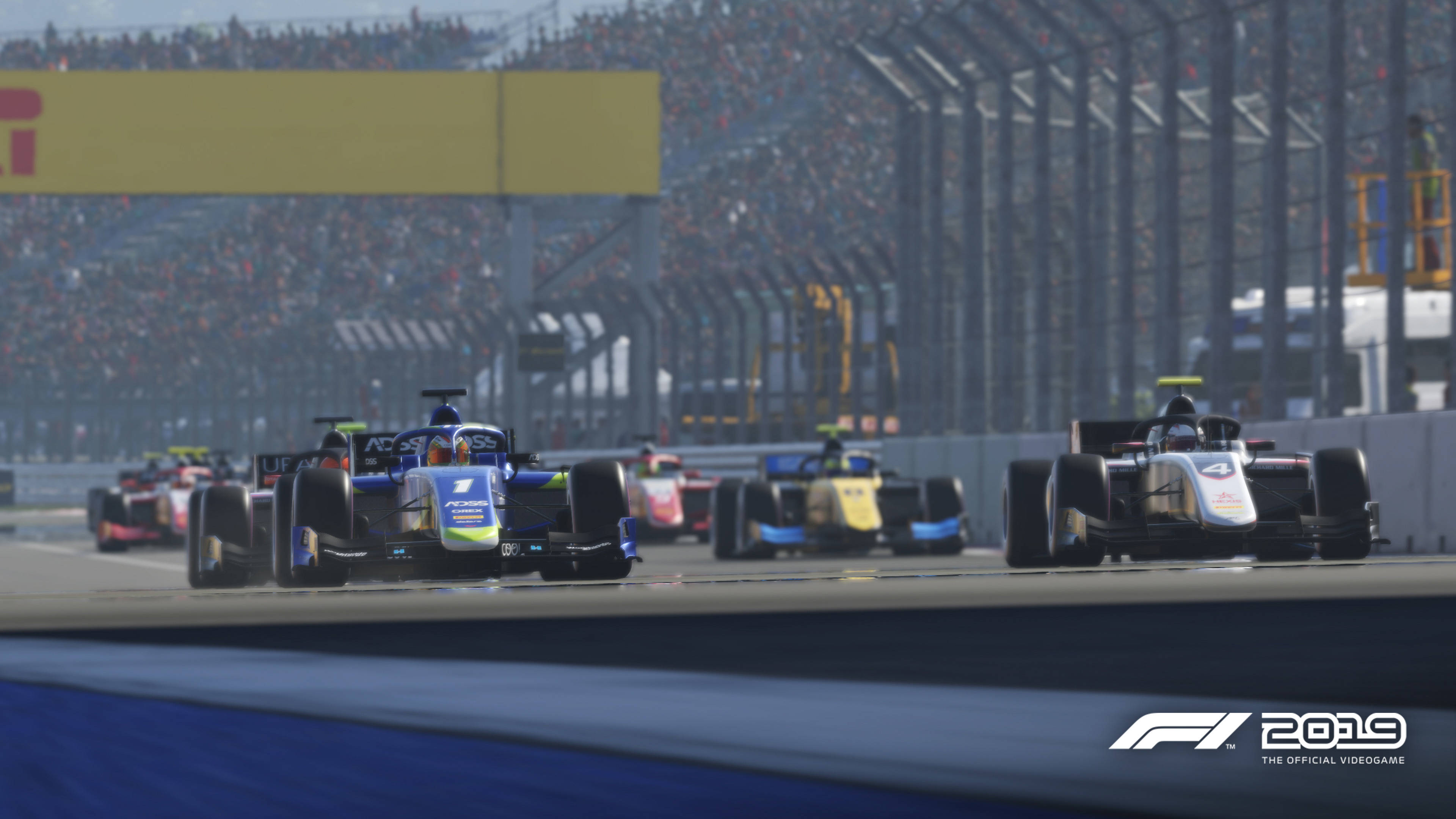 F1 2019 壁紙 桌布 壁紙 — 一級方程式賽車在陽光明媚的賽道上奔馳，背景是擠滿觀眾的看台。