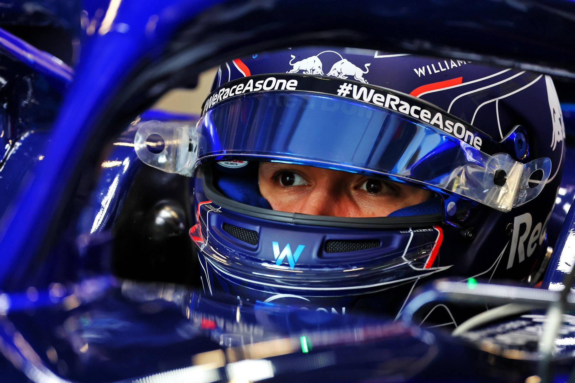 F1 桌布 壁紙 — 一級方程式賽車手在賽車駕駛艙內，透過藍色頭盔面罩可見其專注眼神的特寫。