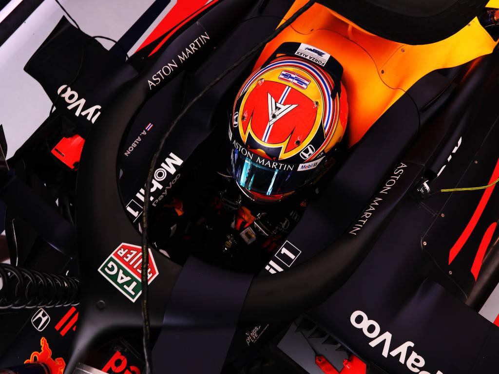 F1 桌布 壁紙 — 一級方程式賽車手頭盔的特寫，位於 Aston Martin 賽車的駕駛艙內，帶有鮮豔的橙色和黑色塗裝。