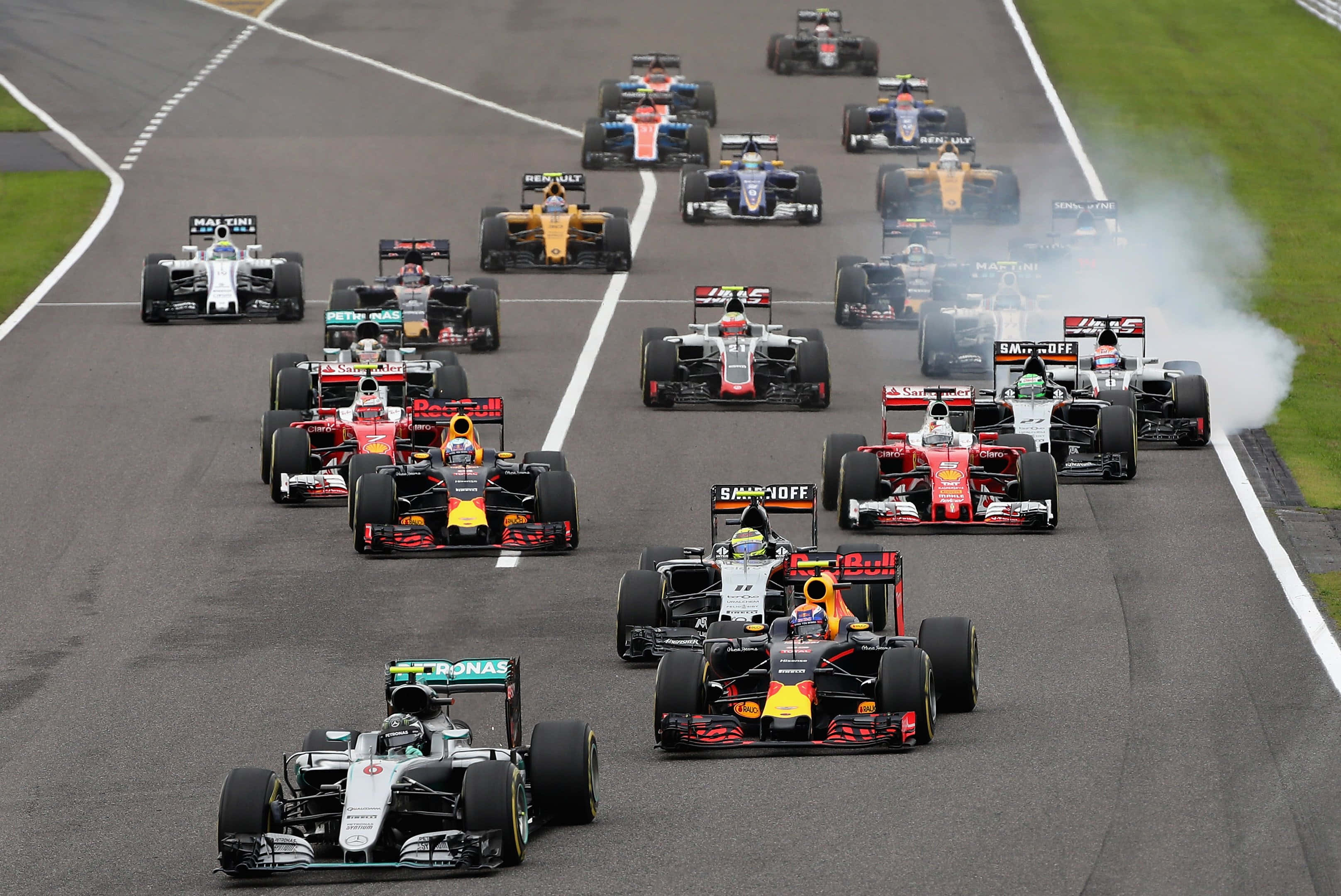 HD F1 2016 桌布 壁紙 — 一級方程式賽車群在濕滑賽道上緊密競賽，後輪冒出滾滾濃煙。