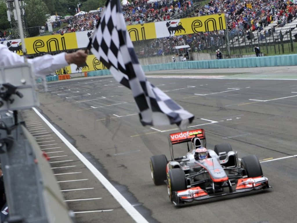 Chequered Flag 桌布 壁紙 — 一級方程式賽車越過終點線，旗手揮動方格旗宣布勝利。