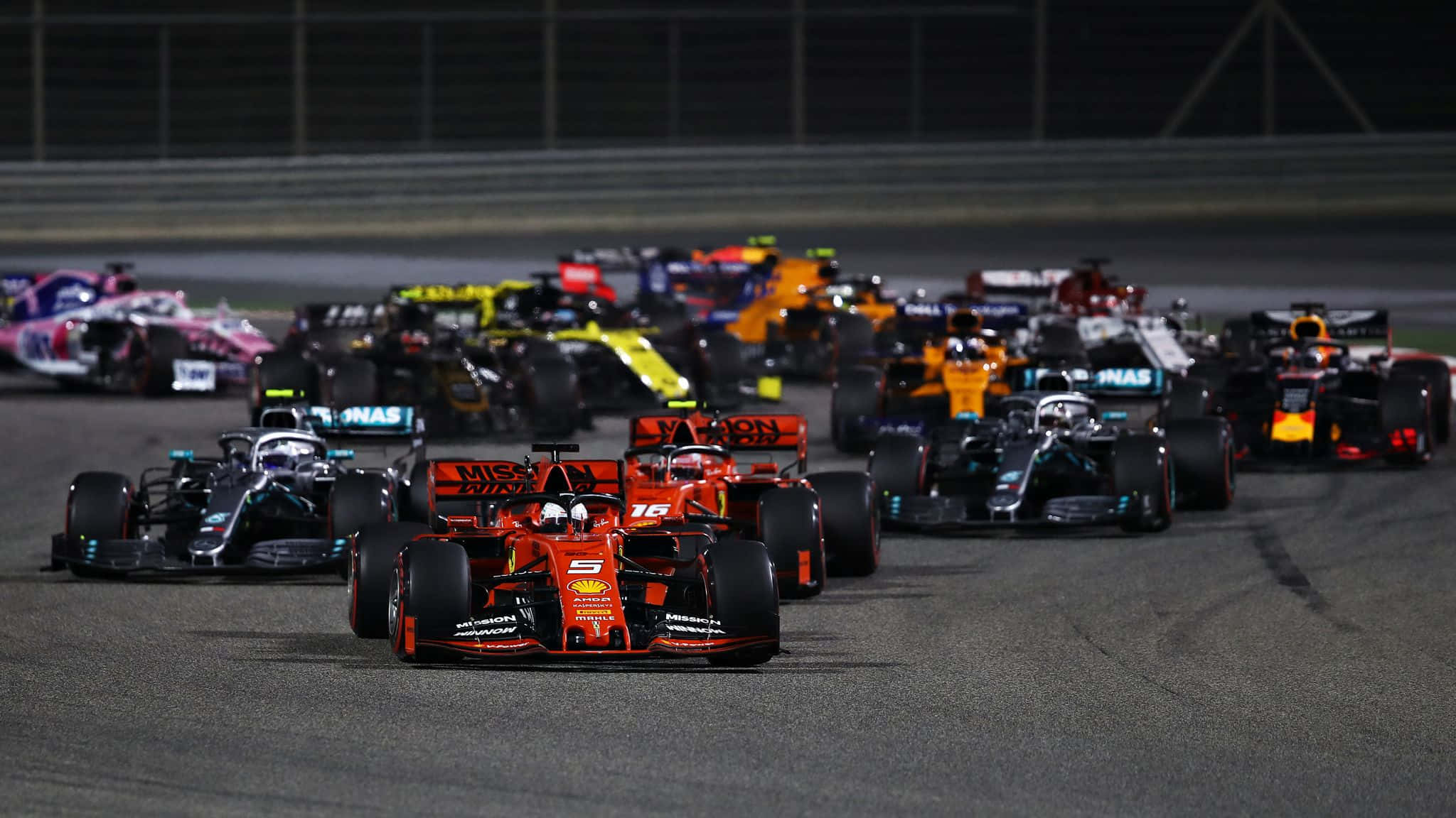 F1 2019 壁紙 桌布 壁紙 — 一級方程式賽車車群在夜間於賽道上，在明亮的泛光燈下緊密競賽。