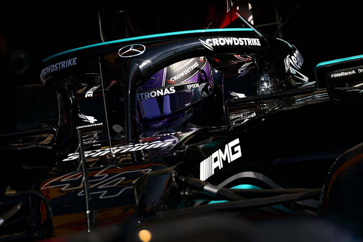 F1 桌布 壁紙 — 一級方程式車手在黑色和青綠色的 Mercedes-AMG 賽車中，帶有贊助商標誌，在戲劇性燈光下的特寫。