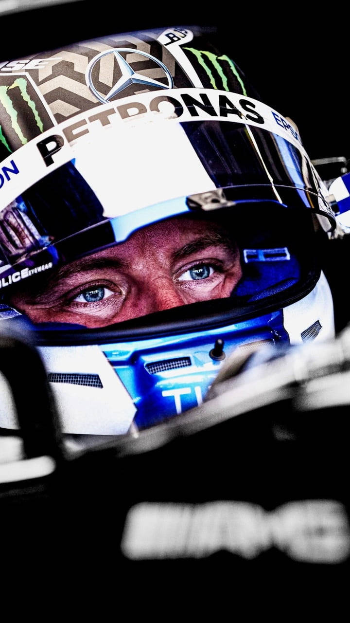 Valtteri Bottas 桌布 壁紙 — 一級方程式車手強烈的藍色眼睛特寫，透過詳細的賽車頭盔可見，頭盔上有Petronas和Monster Energy標誌。