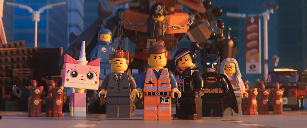 Lego 桌布 壁紙 — 一組LEGO角色，包括蝙蝠俠和獨角貓，在日落時分的風格化城市景觀中站在一起。