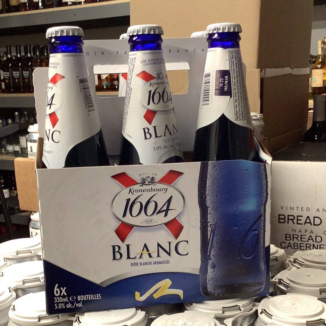 Beer Bottle 桌布 壁紙 — 一組六瓶帶有水珠的Kronenbourg 1664 Blanc啤酒，在商店貨架上與其他飲品一同展示。