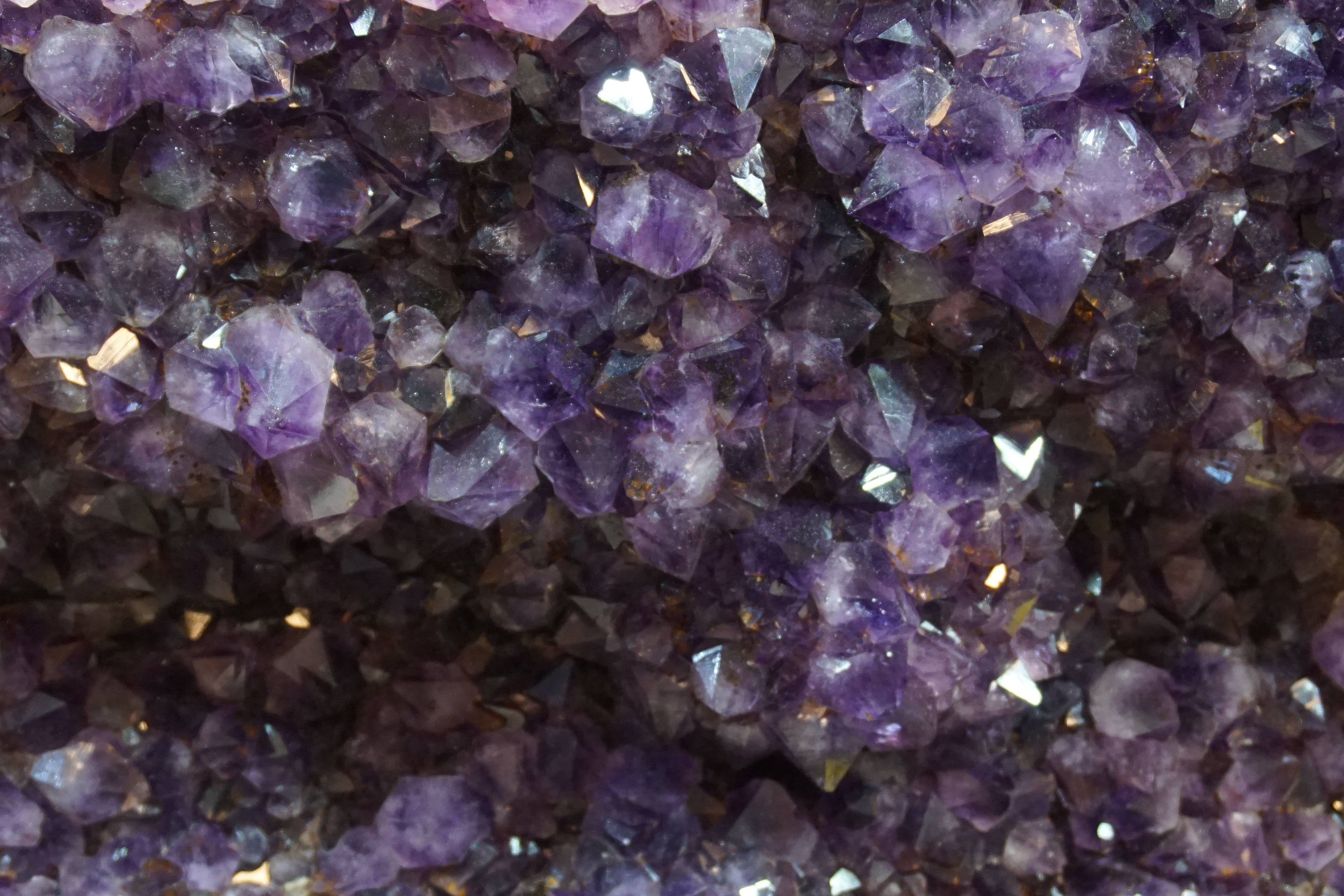 紫水晶 桌布 壁紙 — 一組密集的閃亮紫色紫水晶晶體特寫，晶體具有銳利的切面，捕捉光線。
