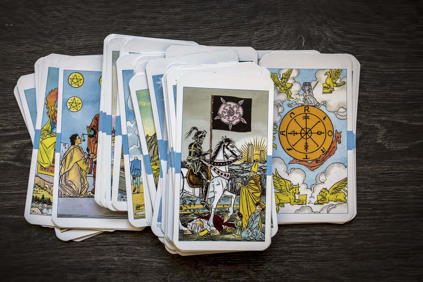 Tarot Card 桌布 壁紙 — 一組復古塔羅牌，帶有精細插圖，呈扇形散開在深色木質表面上。