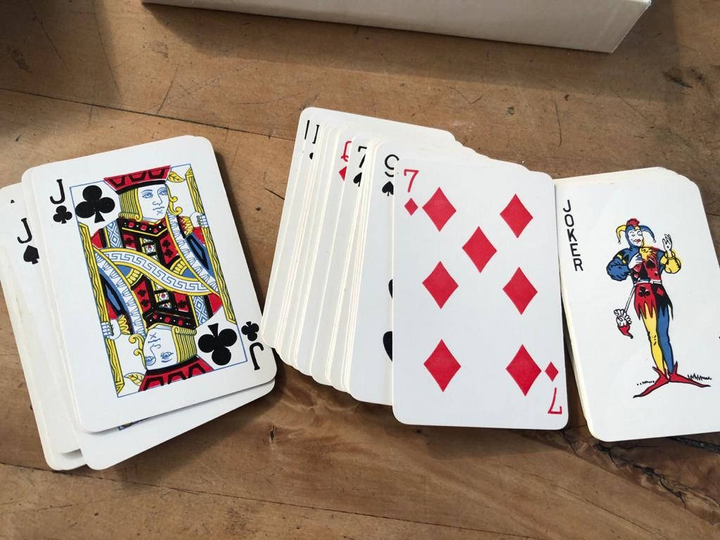 Playing Cards 桌布 壁紙 — 一組撲克牌，包括傑克、小丑和七，在質樸的木桌上扇形展開。