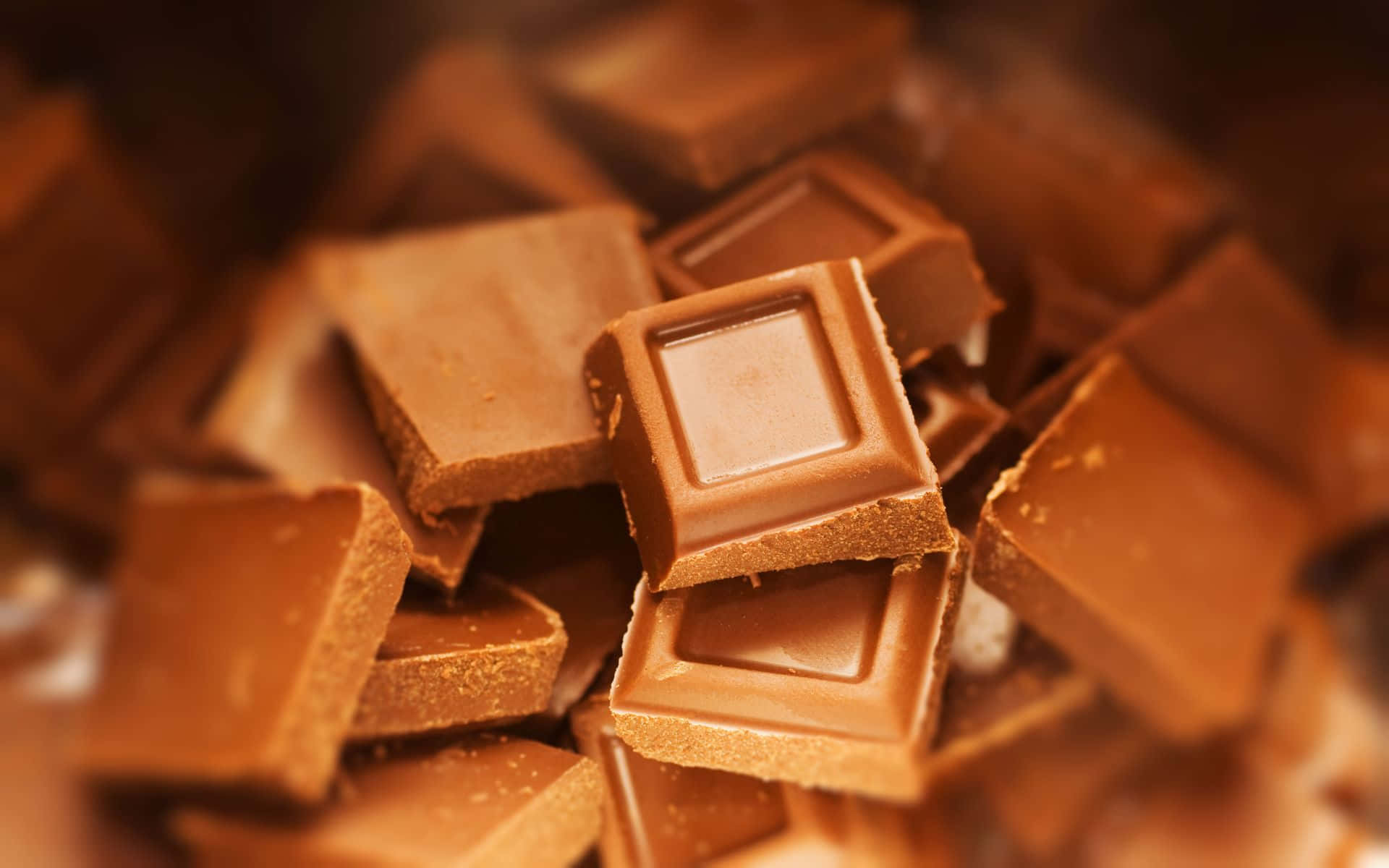 Brown Chocolate 桌布 壁紙 — 一組濃郁的棕色巧克力方塊堆疊在一起的近距離特寫，採用柔和焦點和溫暖光線。