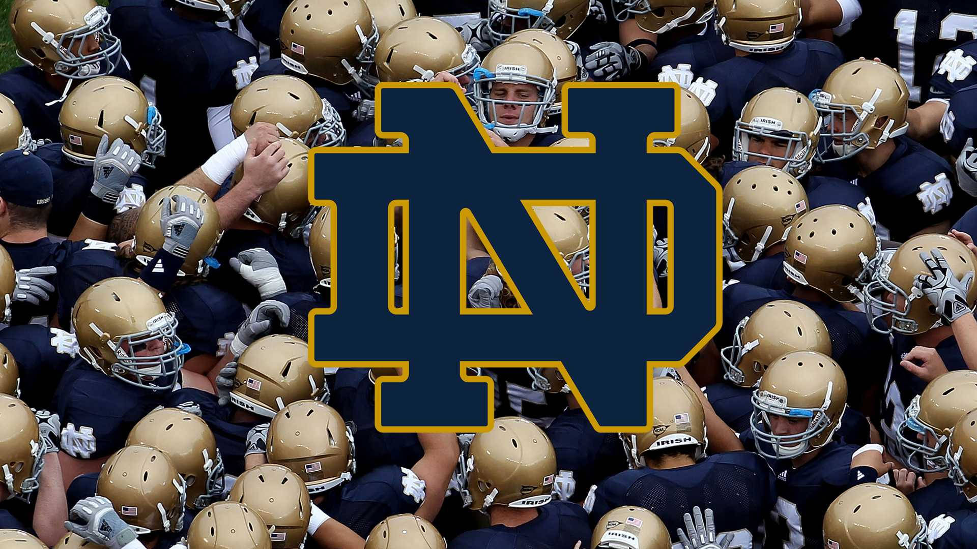 Notre Dame Football 桌布 壁紙 — 一組緊密聚集的聖母大學美式足球員，戴著金色頭盔和深藍色球衣，帶有ND標誌重疊。