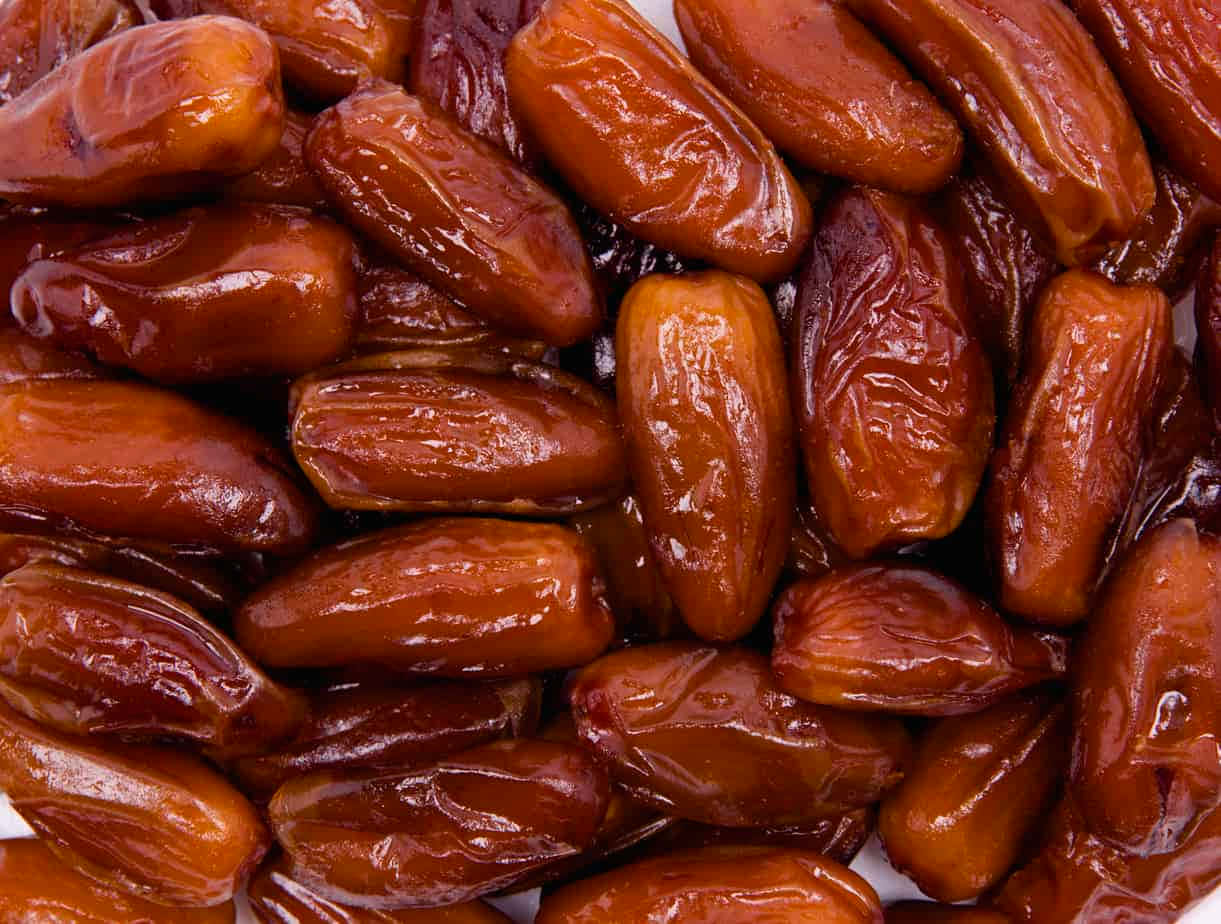 Fruits 桌布 壁紙 — 一組飽滿光澤的棕色椰棗堆疊在一起的近距離特寫，展現出皺紋質感和豐富的焦糖色調。