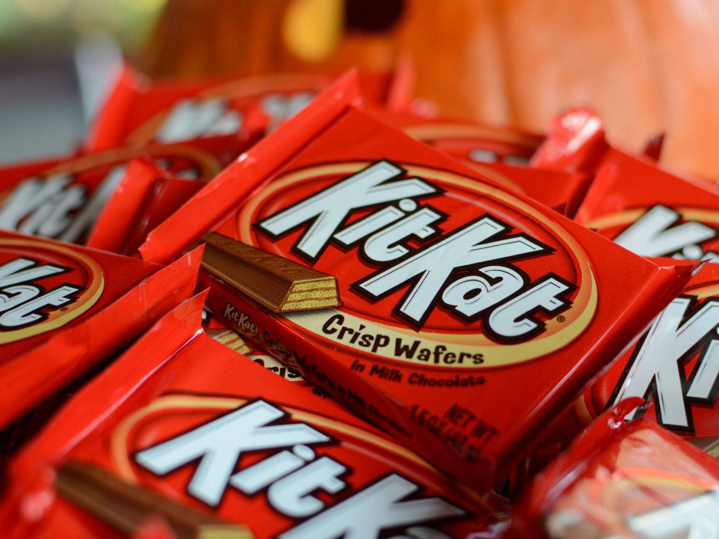 Chocolate 桌布 壁紙 — 一組鮮紅色的KitKat Crisp Wafers包裝堆疊在一起，有塊巧克力威化餅露出來的特寫。