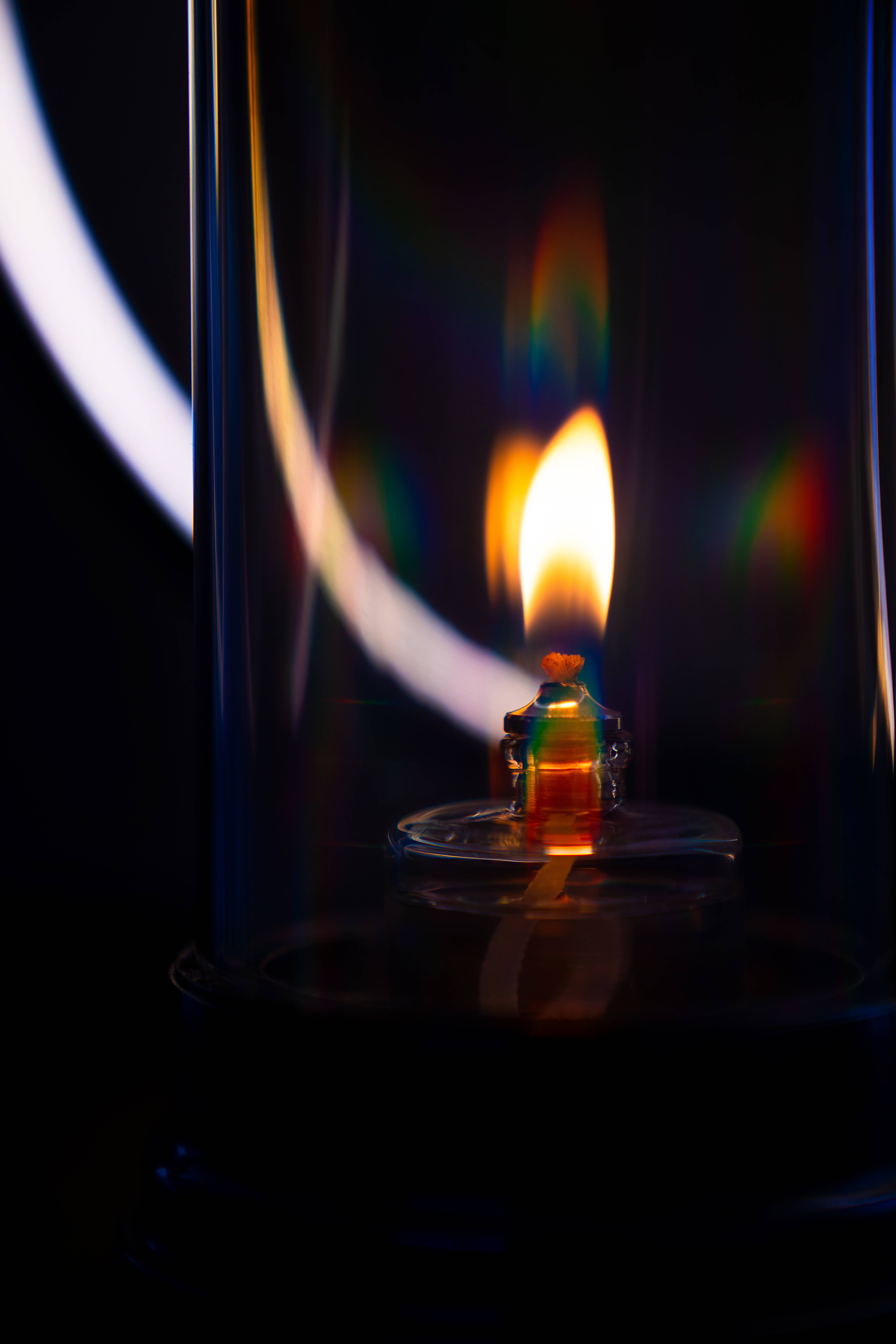 Prism 桌布 壁紙 — 一縷火焰在玻璃燈籠內搖曳，在黑暗背景上投射出彩色棱鏡。