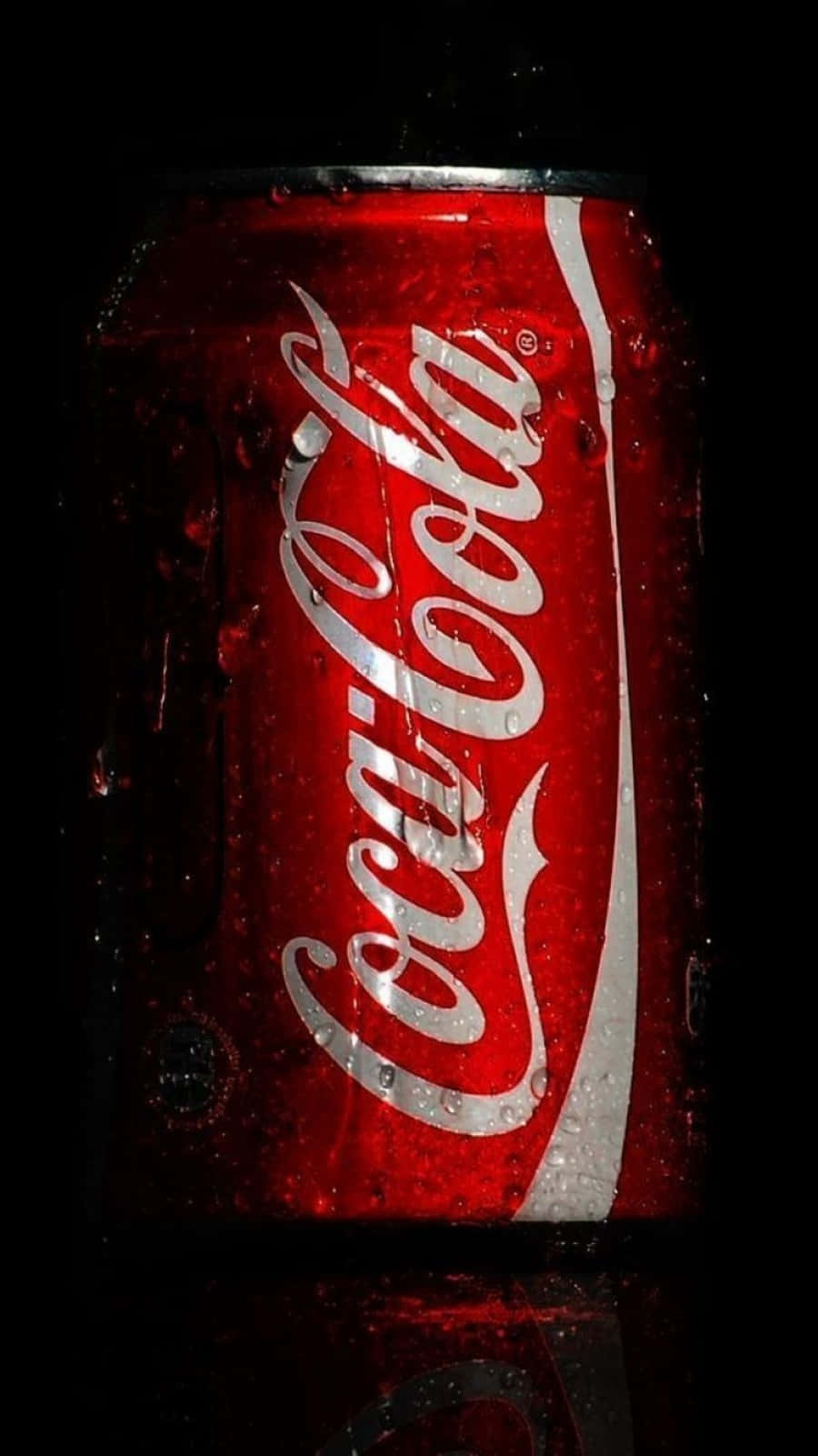 coca cola 桌布 壁紙 — 一罐冰凍的可口可樂在黑色背景上閃爍著冷凝水珠，其標誌性的紅白標誌在聚焦光線下發光。