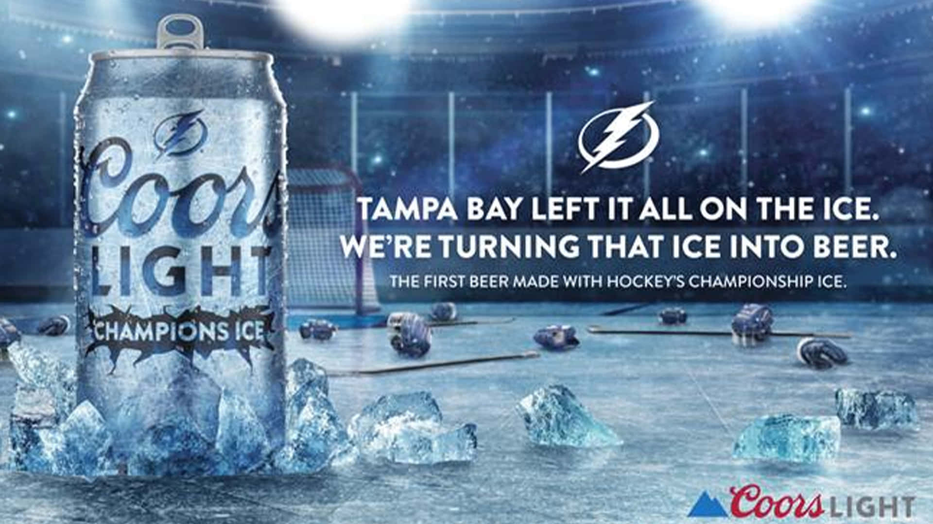Beer Can 桌布 壁紙 — 一罐標有 Champions Ice 的 Coors Light 啤酒罐放在冰球場的冰面上，周圍散落著冰球，上方體育館燈光閃爍。