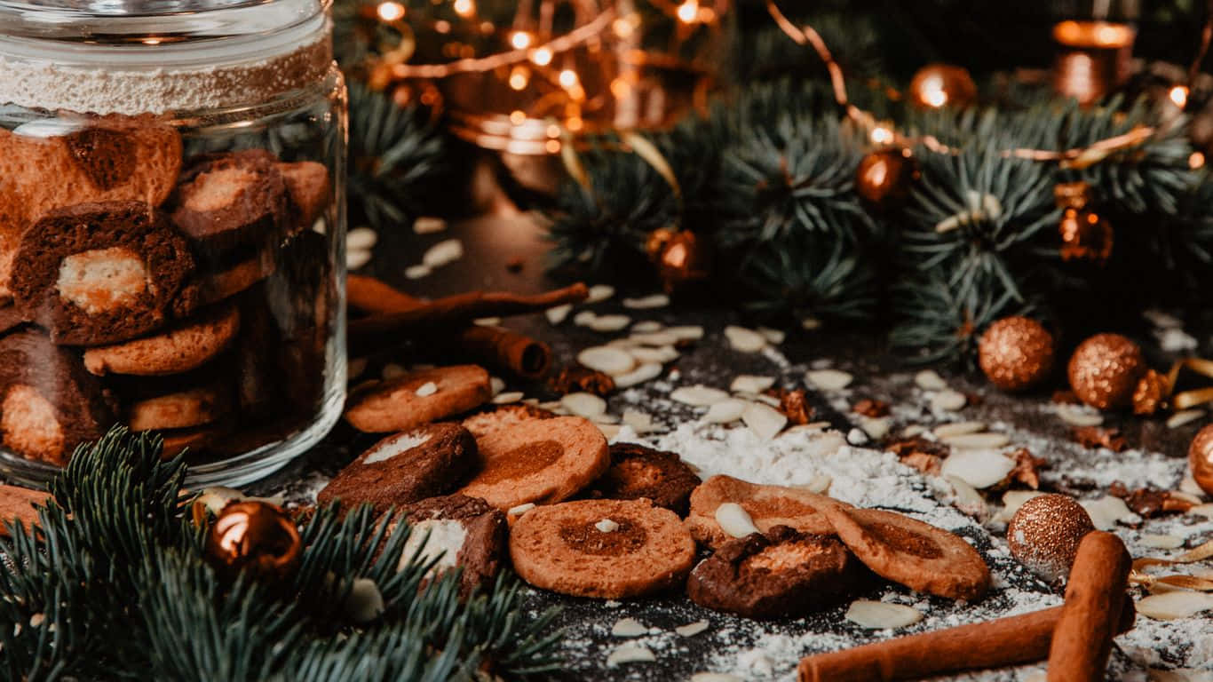 1366x768 Cookies 桌布 壁紙 — 一罐肉桂餅乾將節日美食灑在一個裝飾著松樹、亮粉和溫暖燈串的深色表面上。