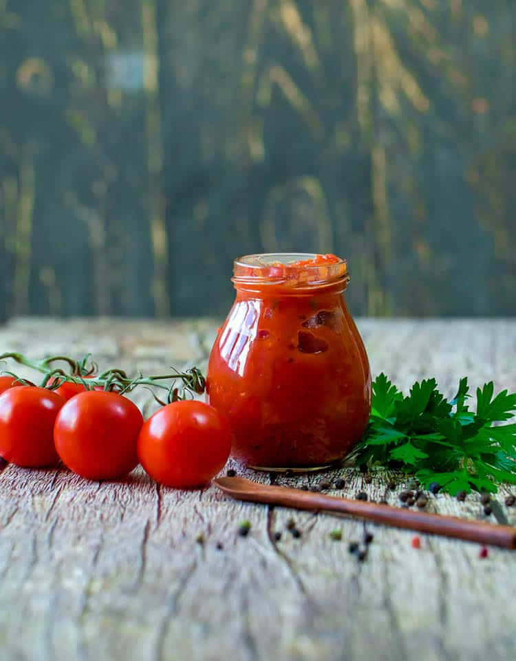 Red Sauce 桌布 壁紙 — 一罐鮮紅番茄醬放在鄉村風木桌上，旁邊有新鮮小番茄、巴西里和胡椒粒。